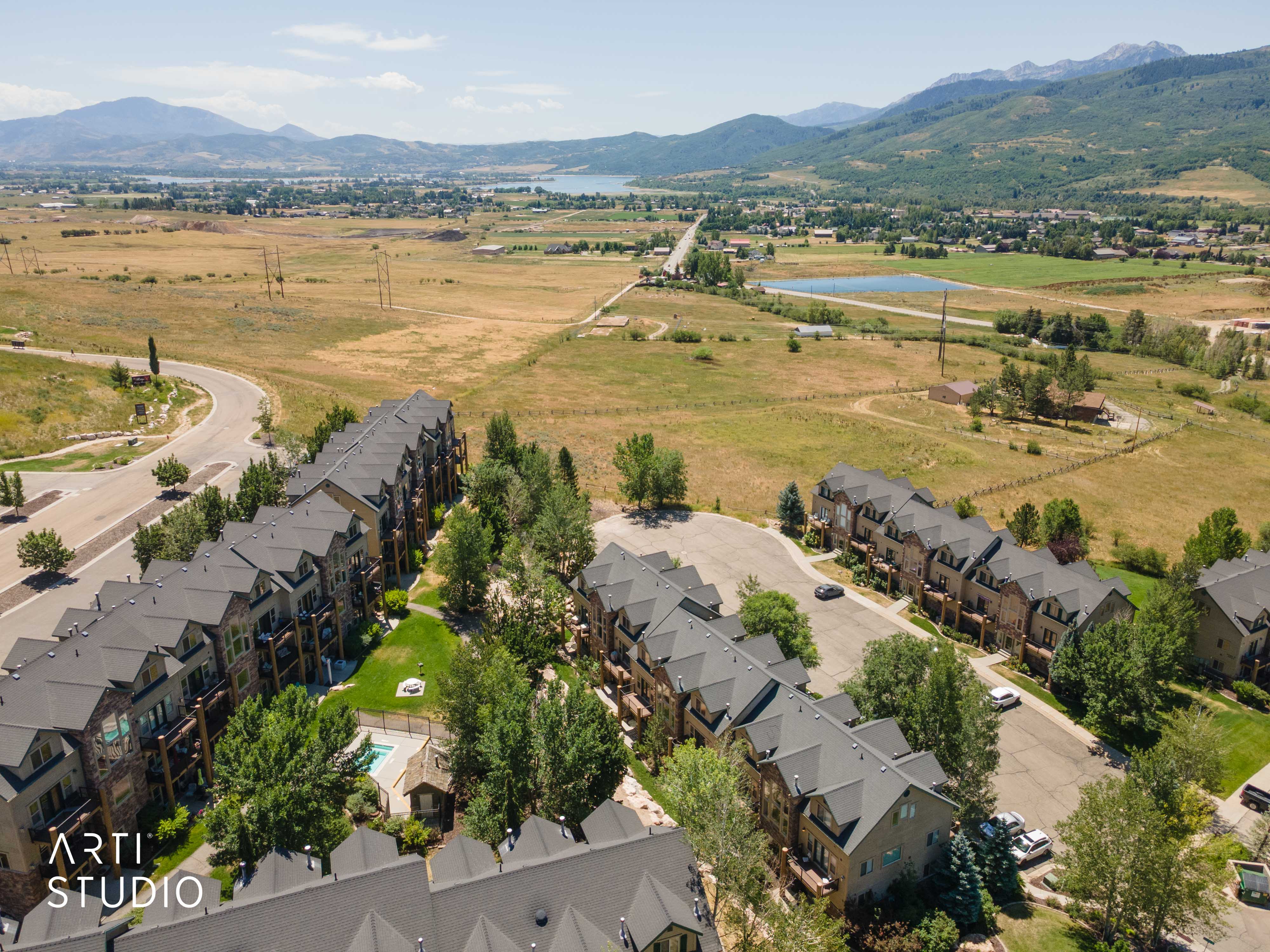 Expansive community featuring multi-story townhomes with dark roofing and stone facades