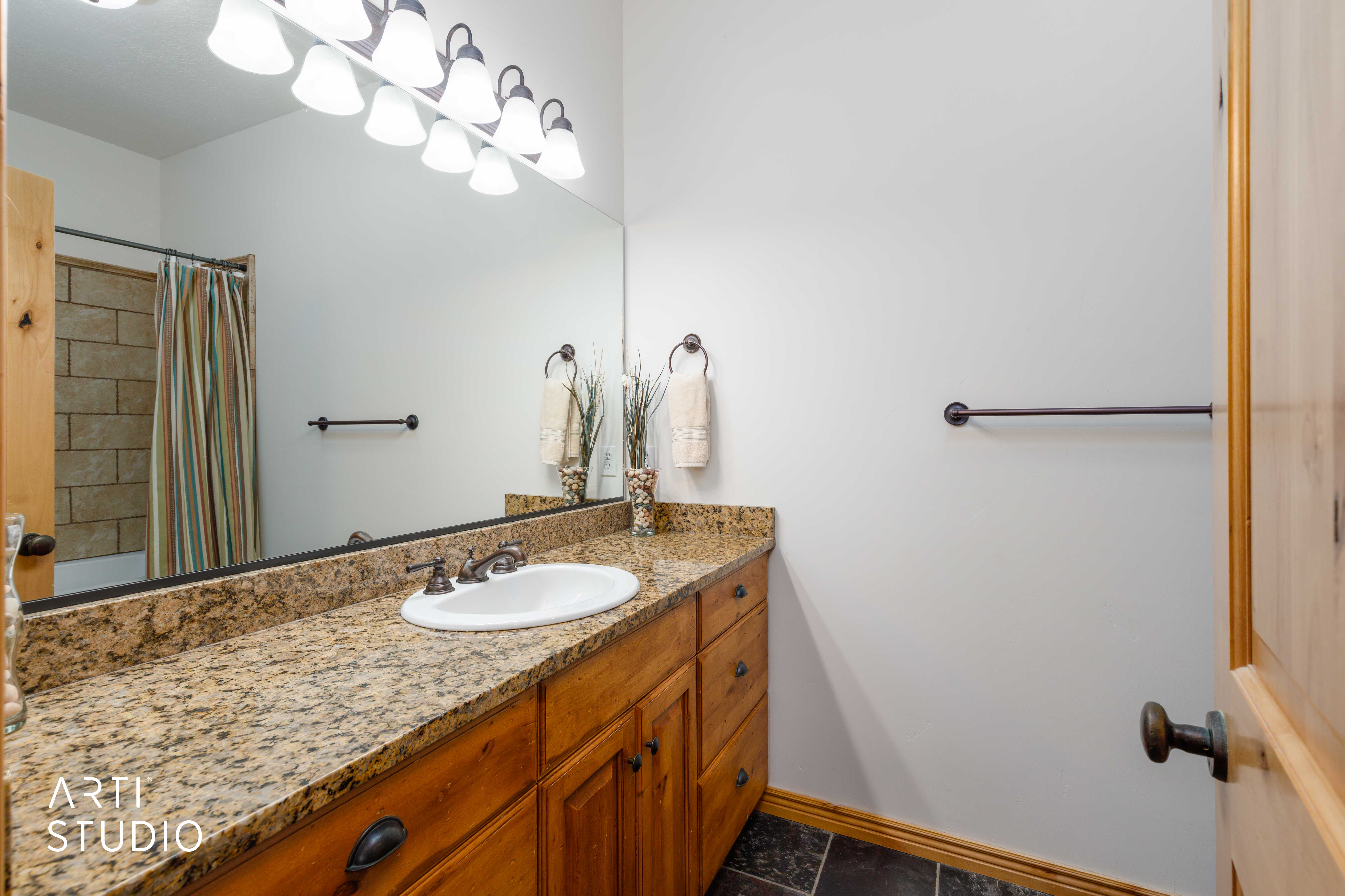 Bathroom featuring a light wood vanity with an integrated sink, granite countertop, and dark bronze hardware