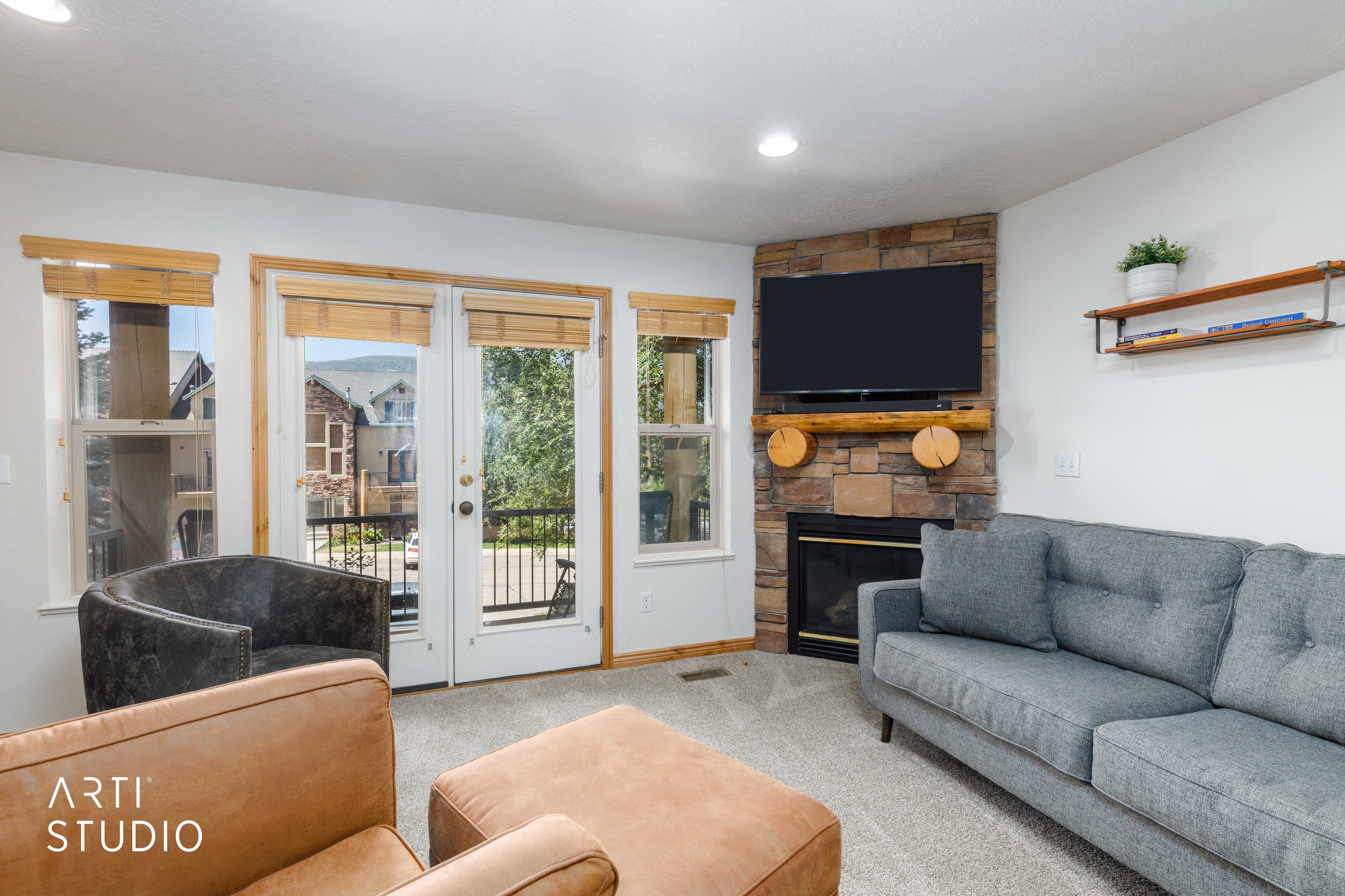 Living area featuring a floor-to-ceiling stone fireplace with a wood mantel, recessed lighting, double French doors, and an outdoor balcony