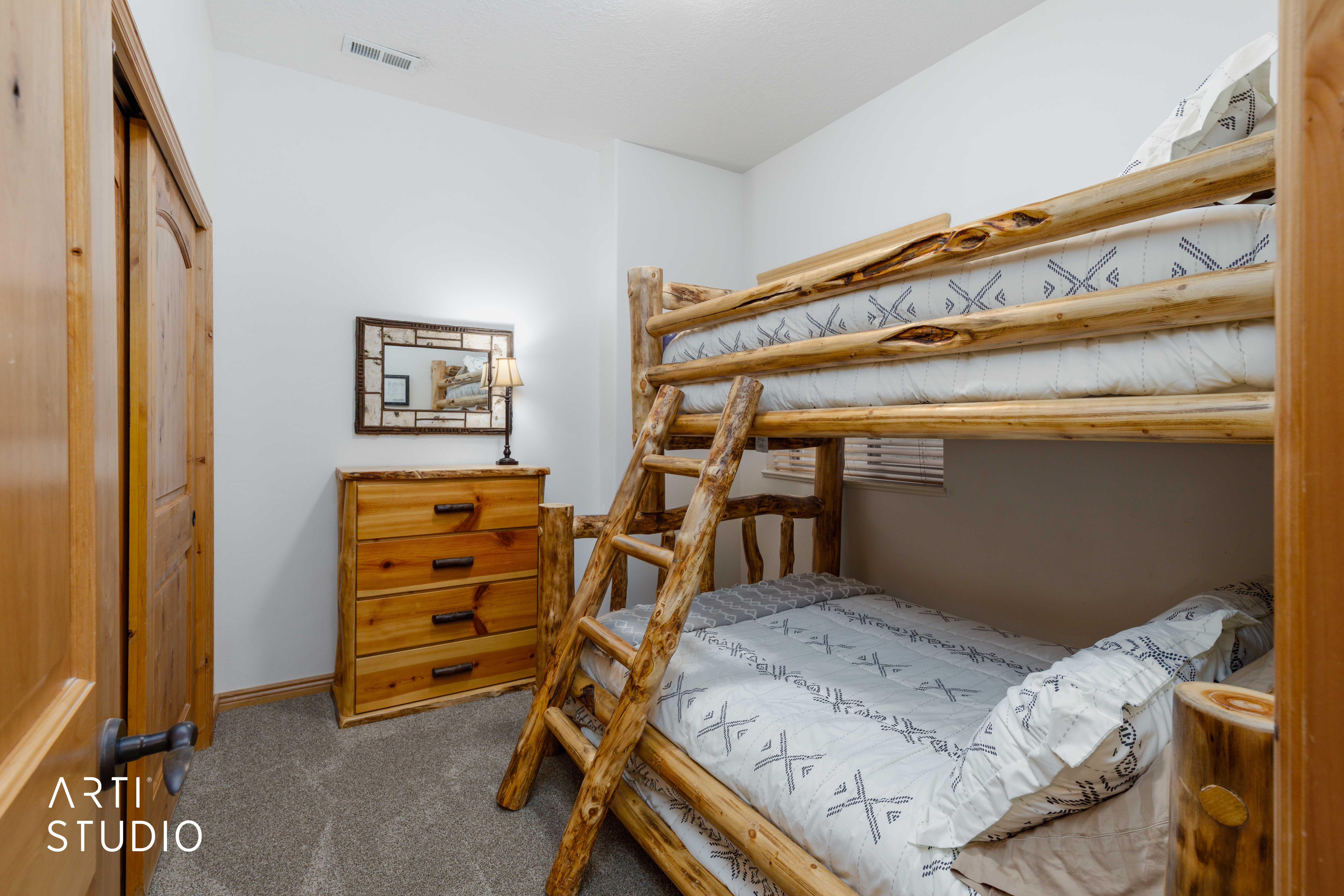 Carpeted room featuring natural wood-finish door, closet with bi-fold doors, and a wood-finish dresser with metal hardware