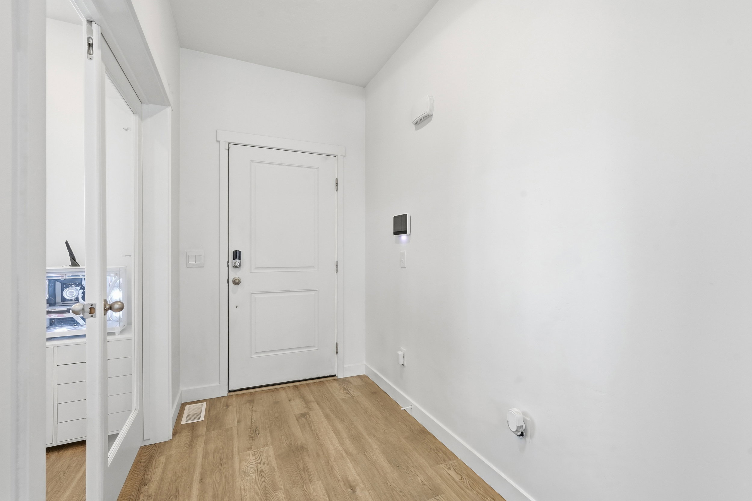Entryway featuring wood-finish flooring, white paneled door, and a glass-paneled interior door