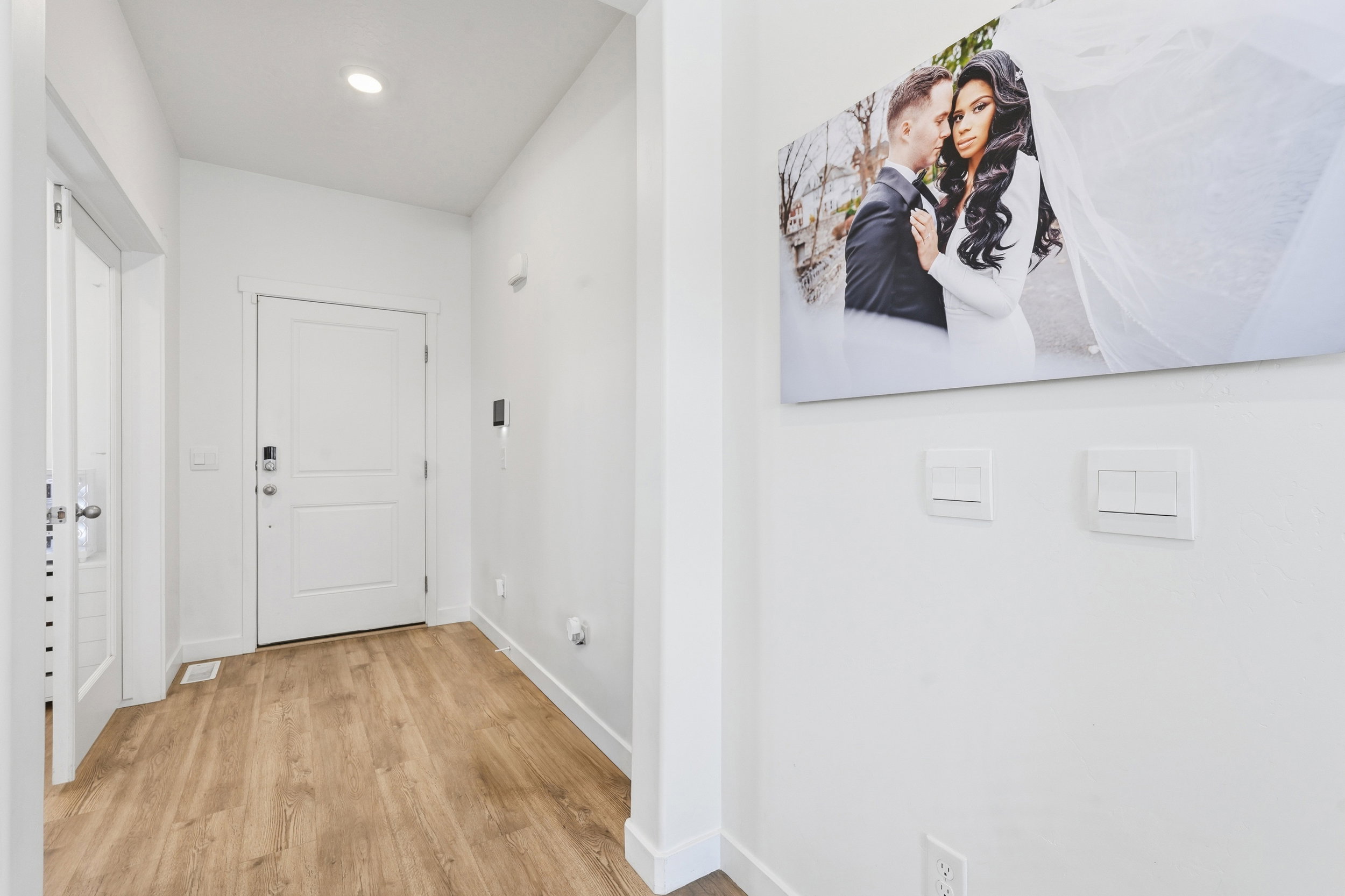 Entryway featuring wood-finish flooring, a contemporary white door, recessed lighting, and crisp white walls