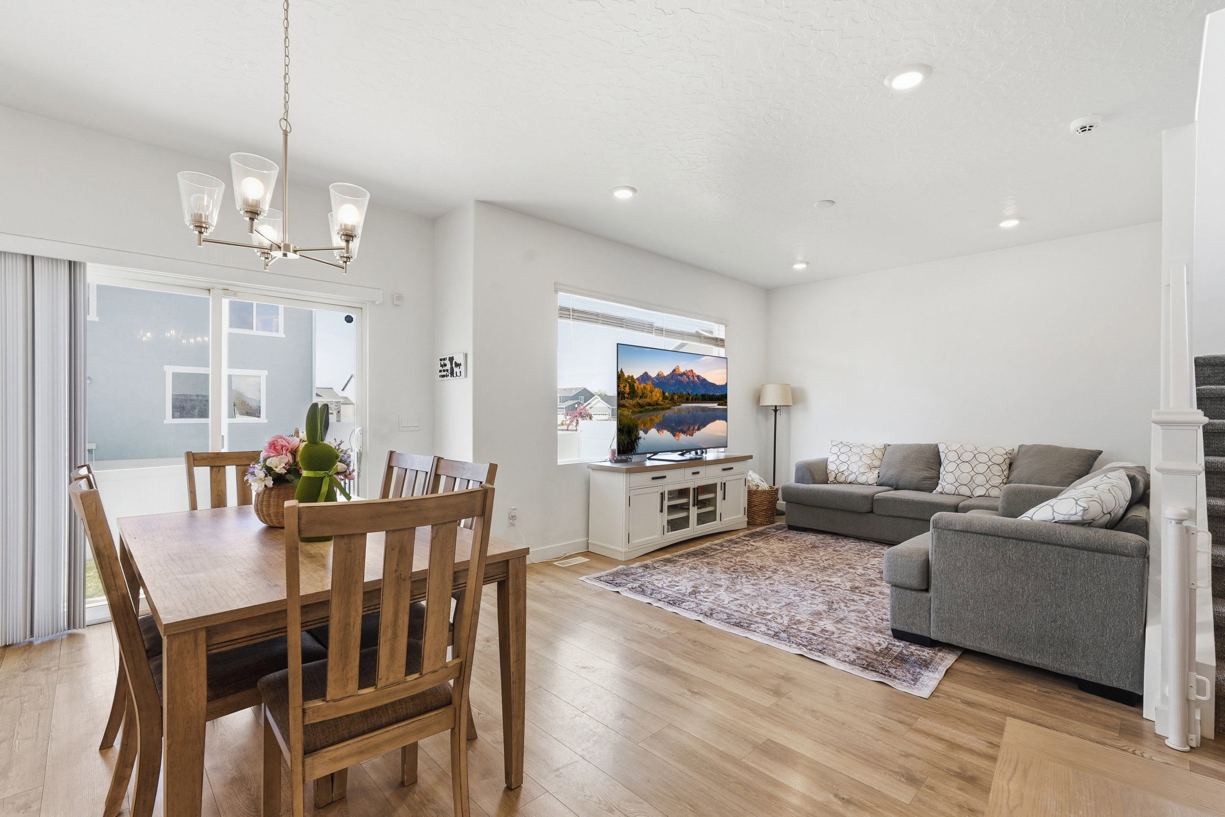 Open-concept living space featuring wood-finish flooring, recessed lighting, and a modern chandelier