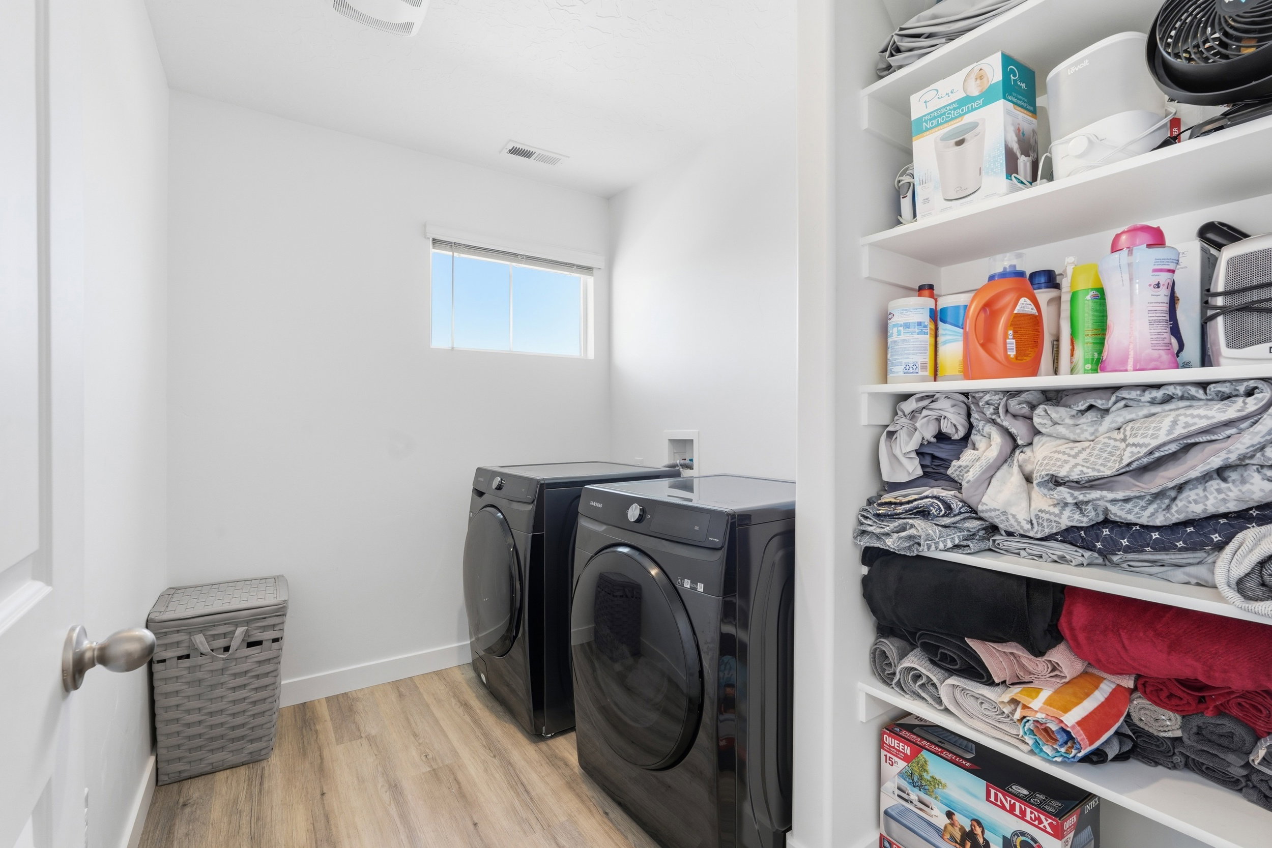 Dedicated laundry area featuring wood-finish flooring, a white-framed window, and built-in shelving
