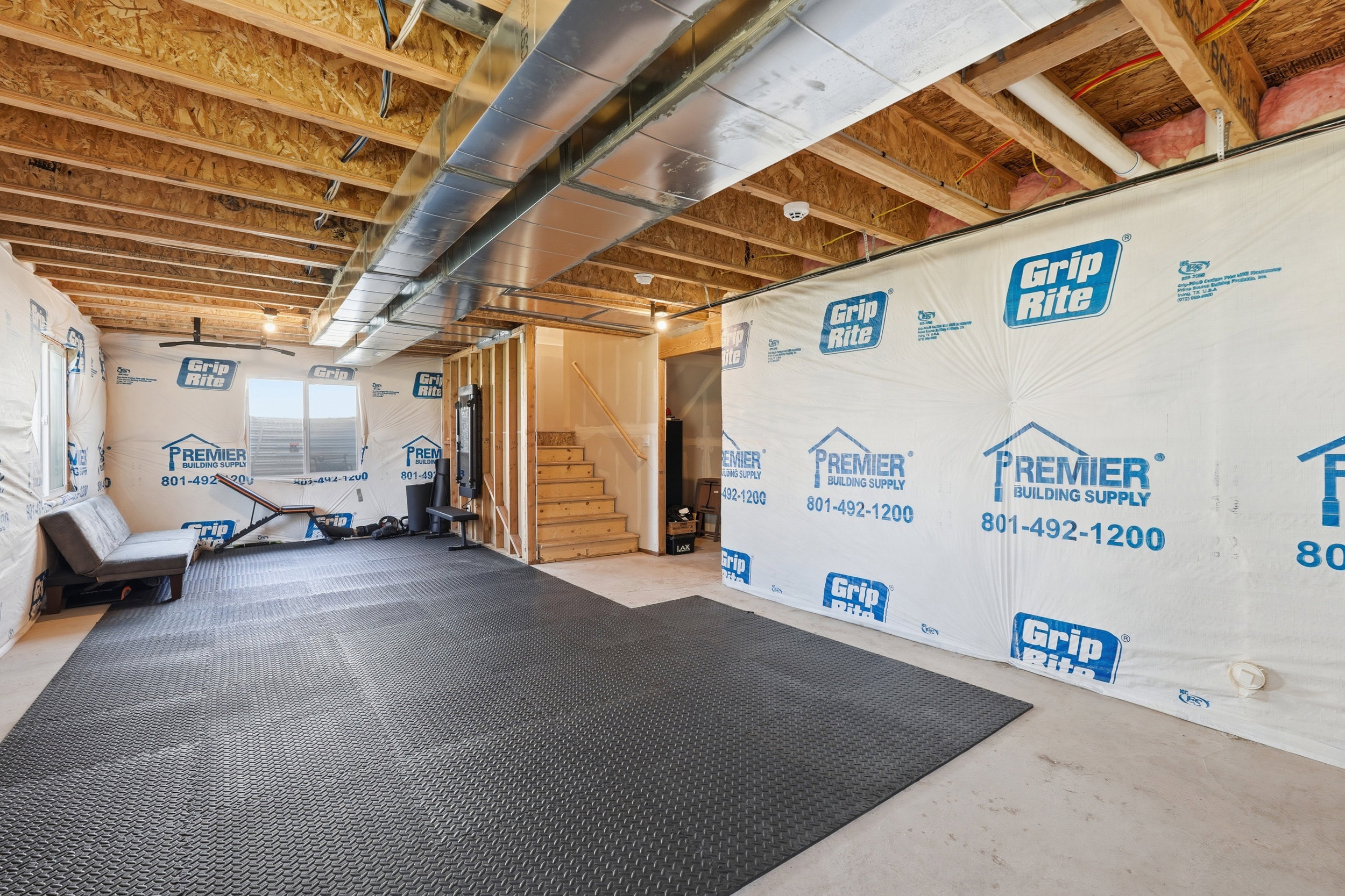 Unfinished basement featuring exposed wood joists and subflooring, partial wood framing for interior walls, and utility ducts