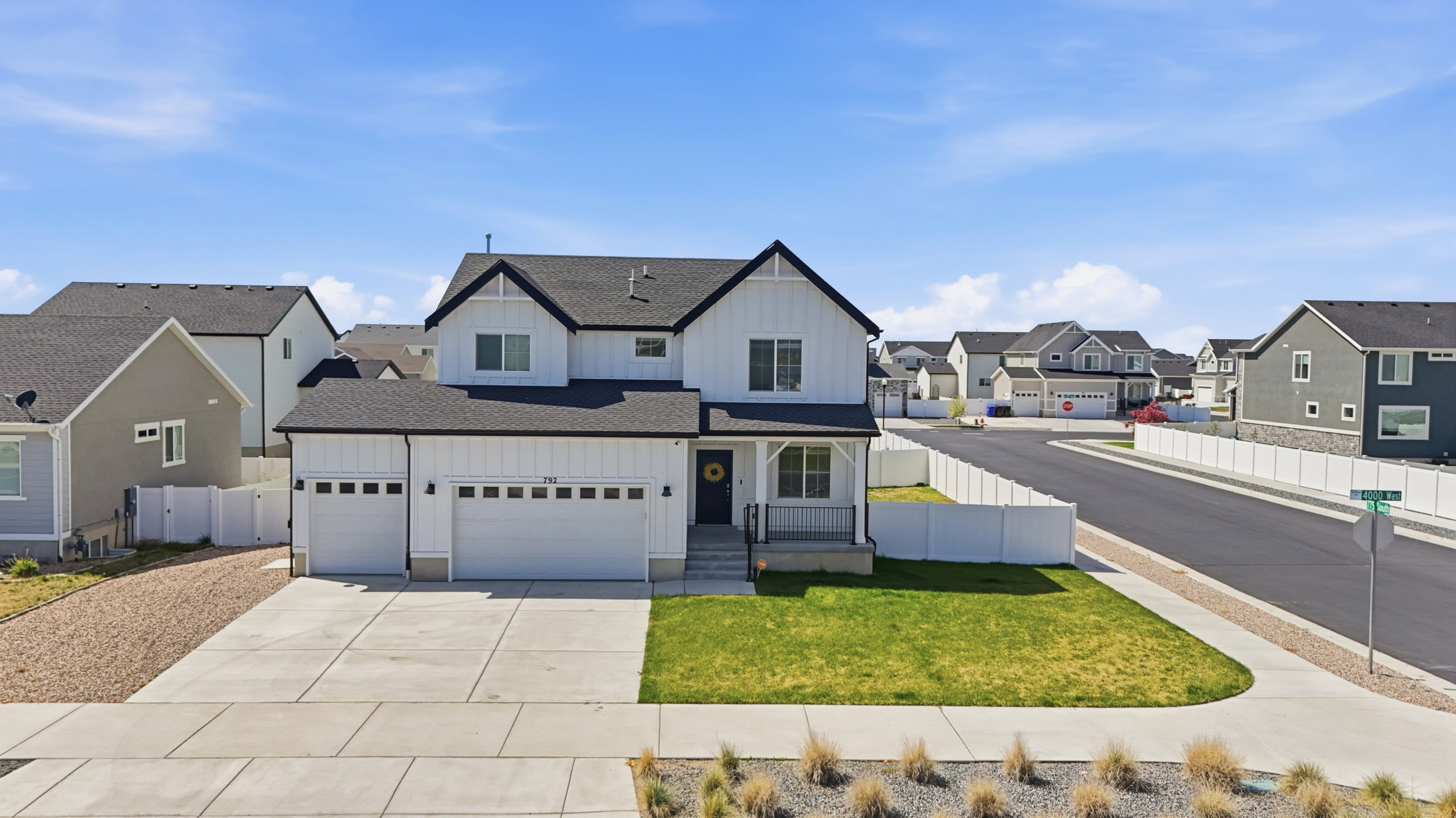 Modern farmhouse-style exterior featuring white siding with black trim accents, a dark shingle roof, and a covered front porch