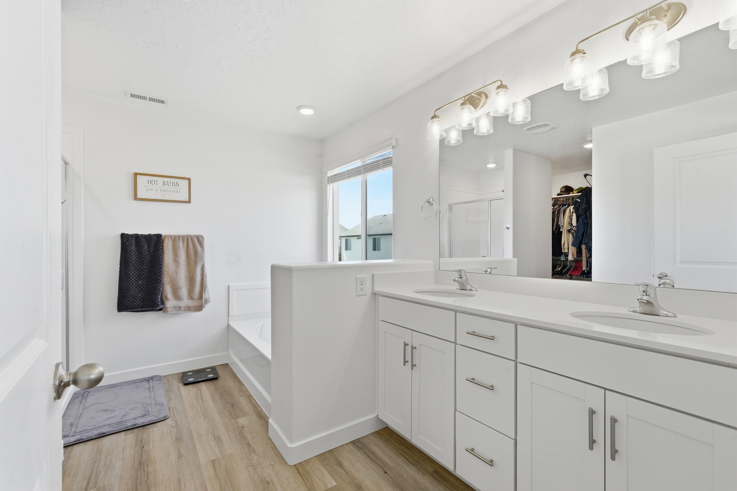 Spacious bathroom featuring a dual vanity with white cabinetry and light-toned countertops