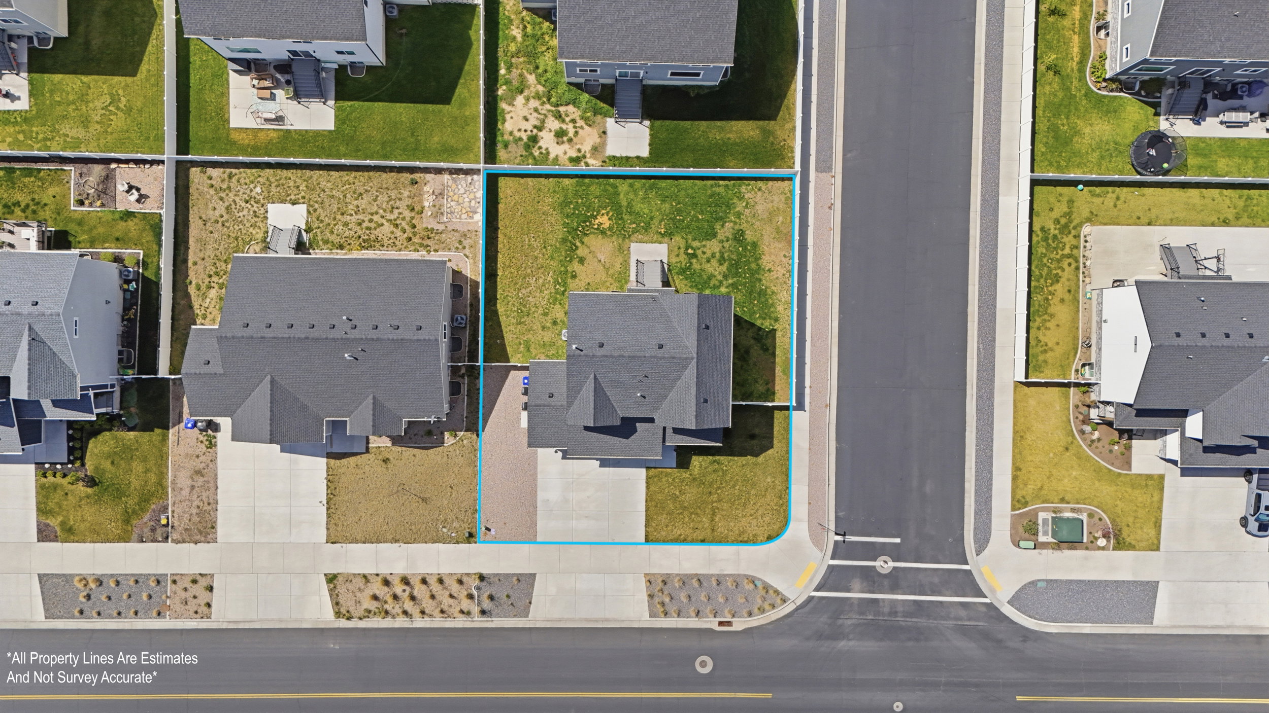 Aerial view showcasing a corner lot property with a dark-pitched roof and light-colored driveway
