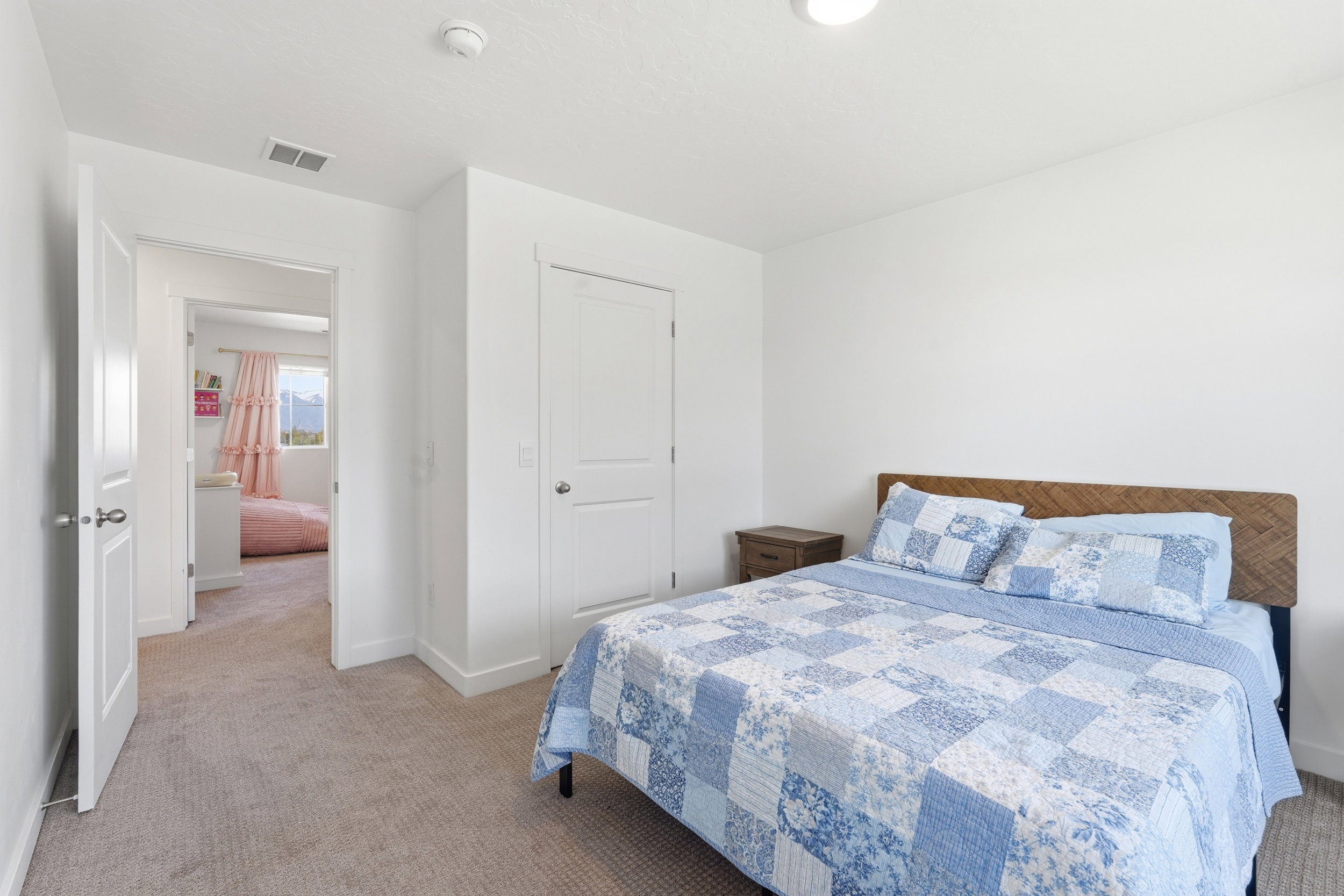 Carpeted bedroom with a wood-finish headboard and white walls