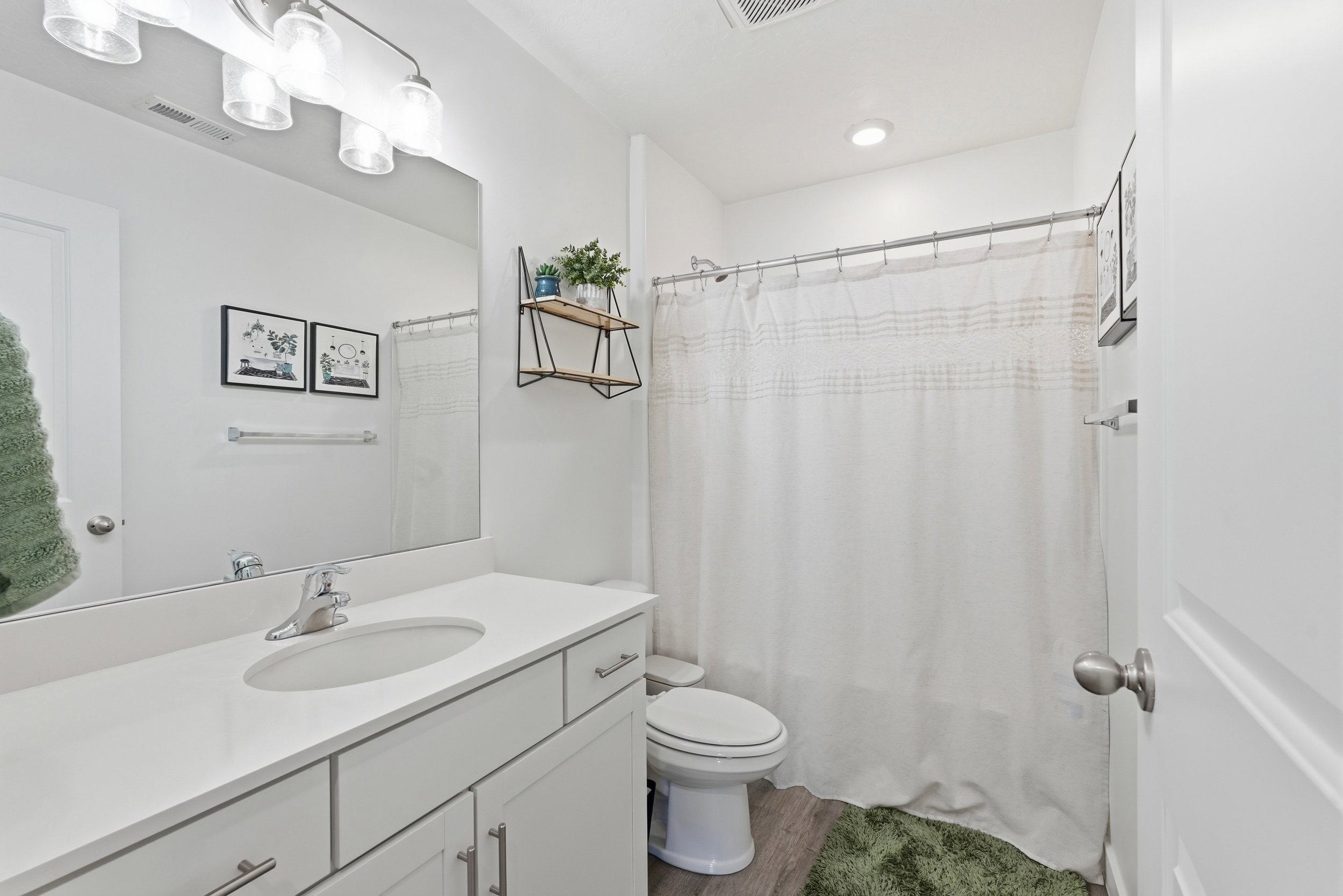 Contemporary bathroom featuring a white vanity with integrated sink, chrome faucet, and expansive mirror