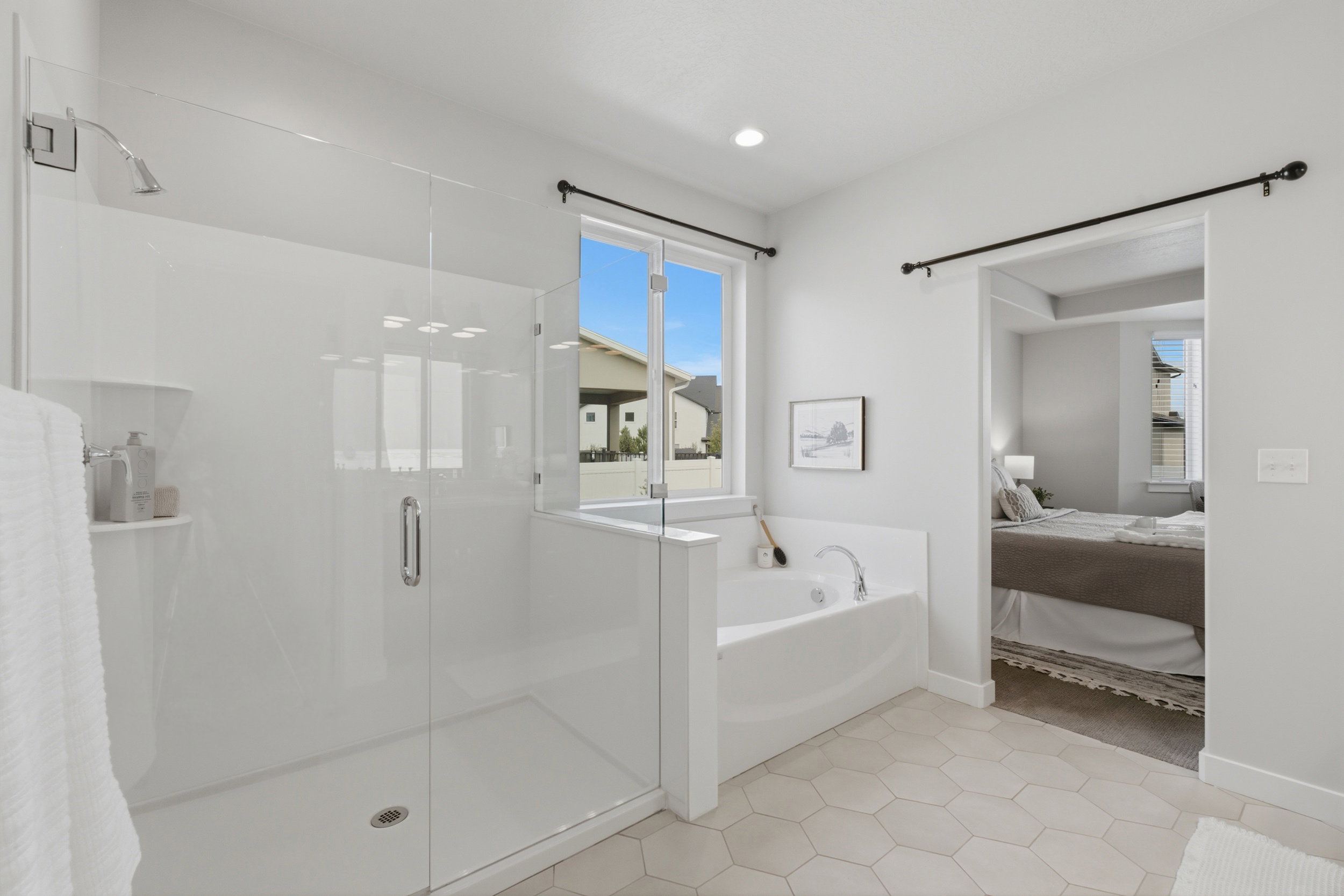 Spacious bathroom featuring a frameless glass shower enclosure, a built-in soaking tub, a window offering exterior light, recessed lighting, and hexagonal floor tile