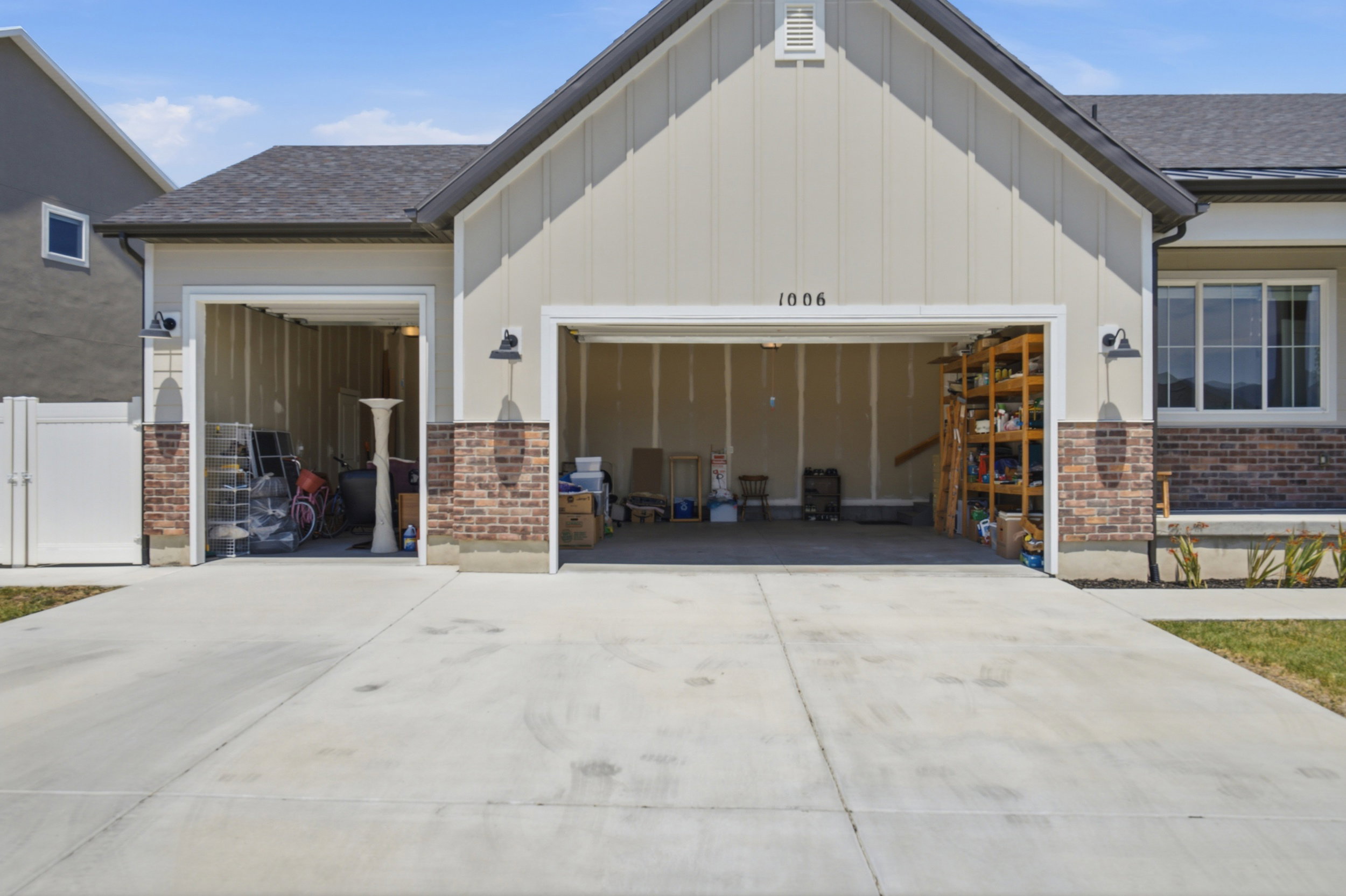 Two-car garage with overhead doors, complemented by brick veneer accents and exterior lighting fixtures