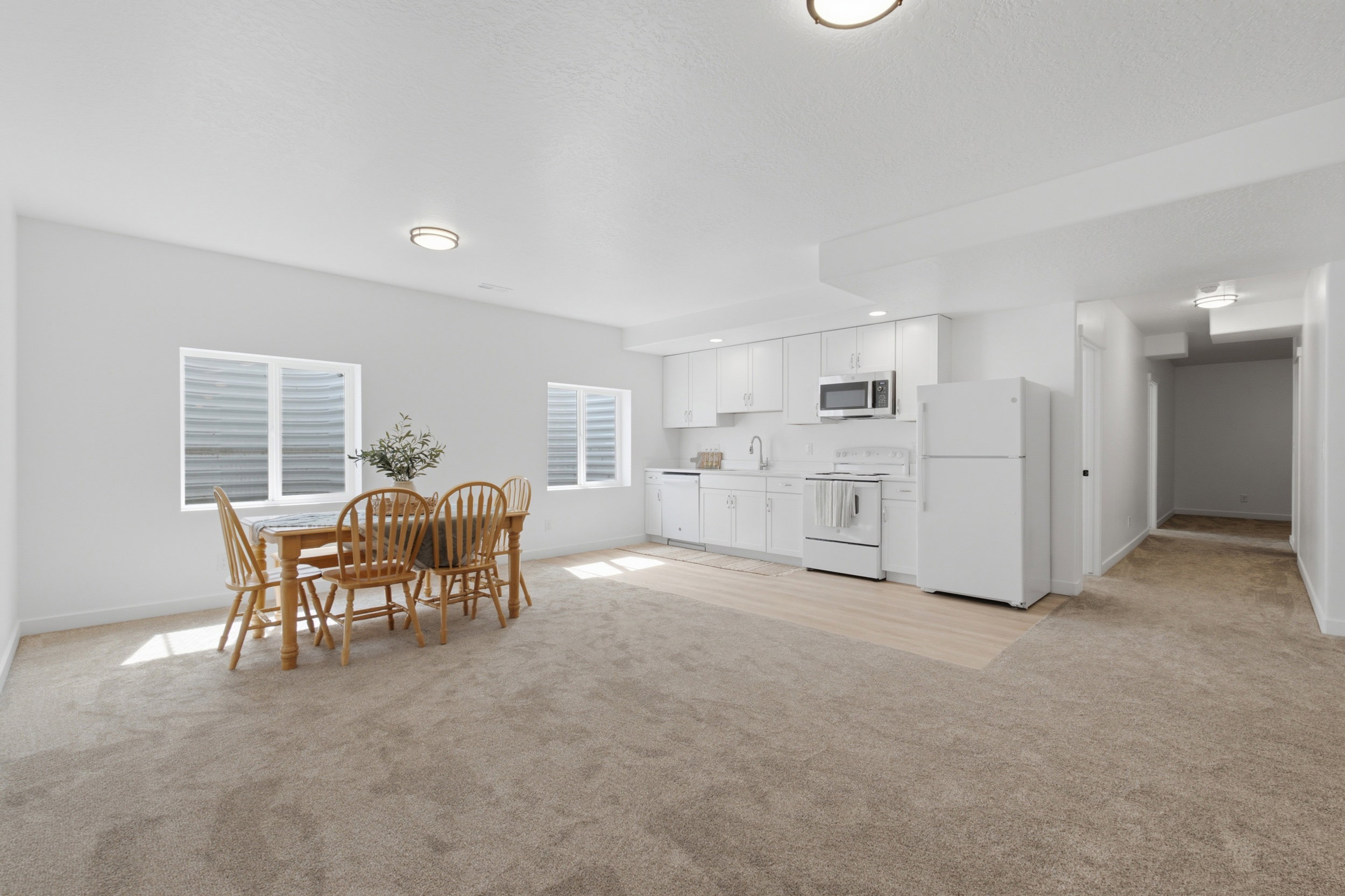 Open-concept living area featuring a kitchen with white cabinetry, a white refrigerator, and a white range