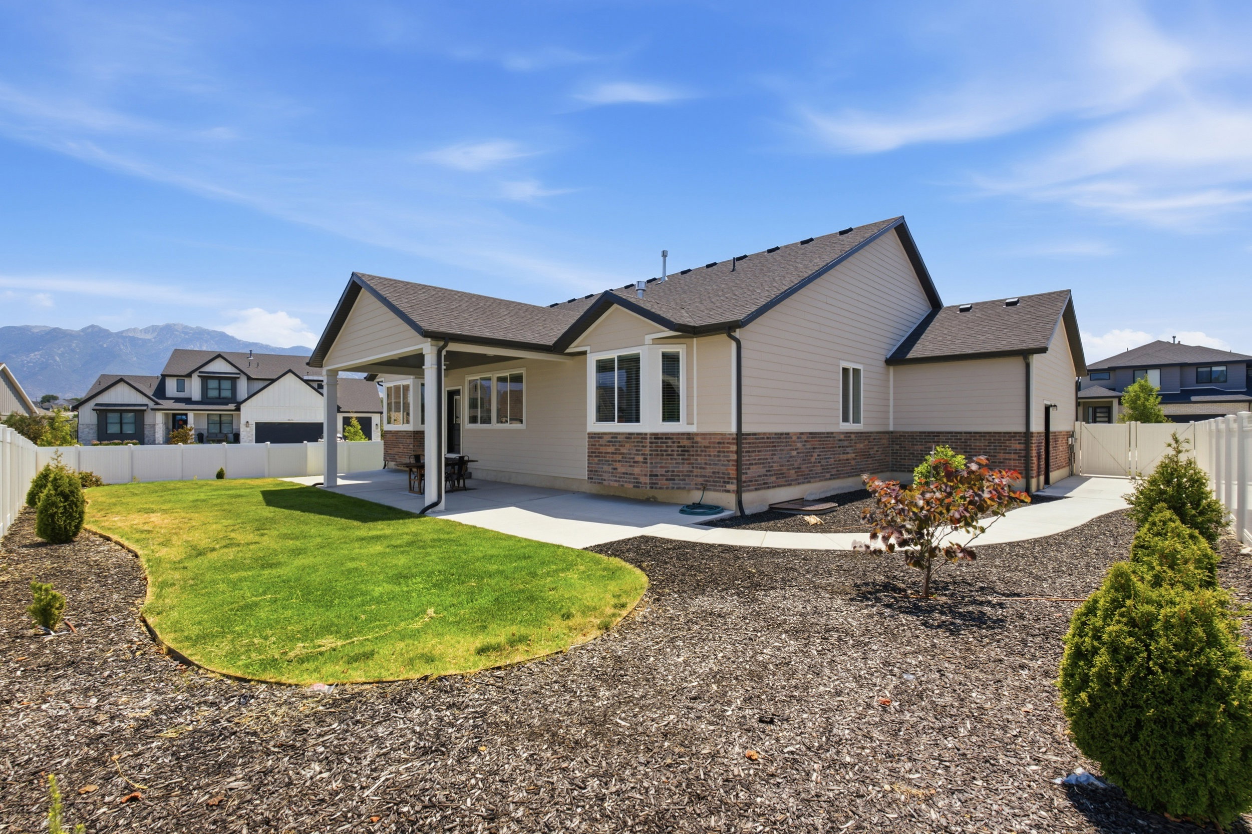 Rear exterior featuring a covered patio, concrete patio, and a manicured lawn