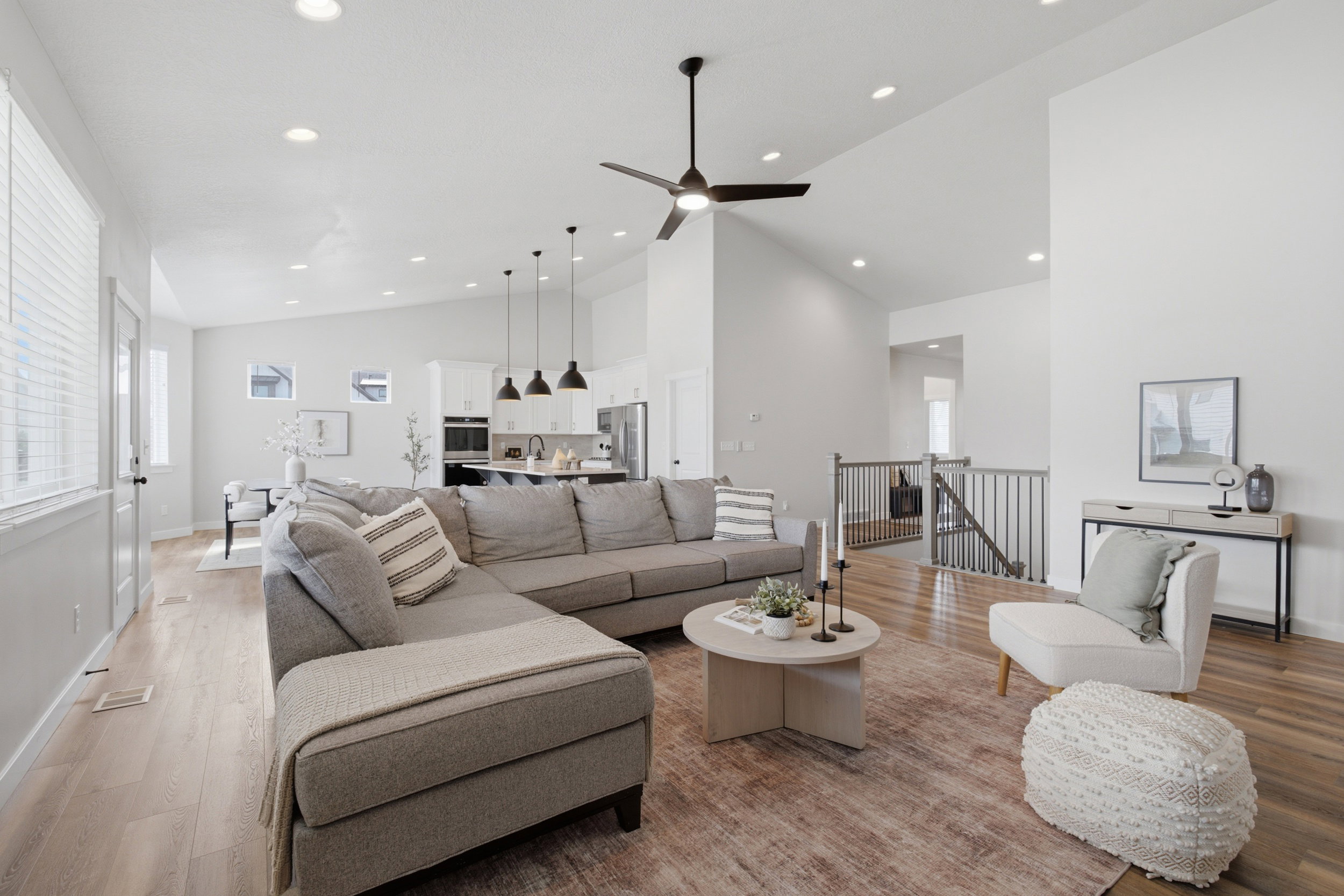 Vaulted ceilings and recessed lighting illuminate this open-concept living space featuring wood-finish flooring