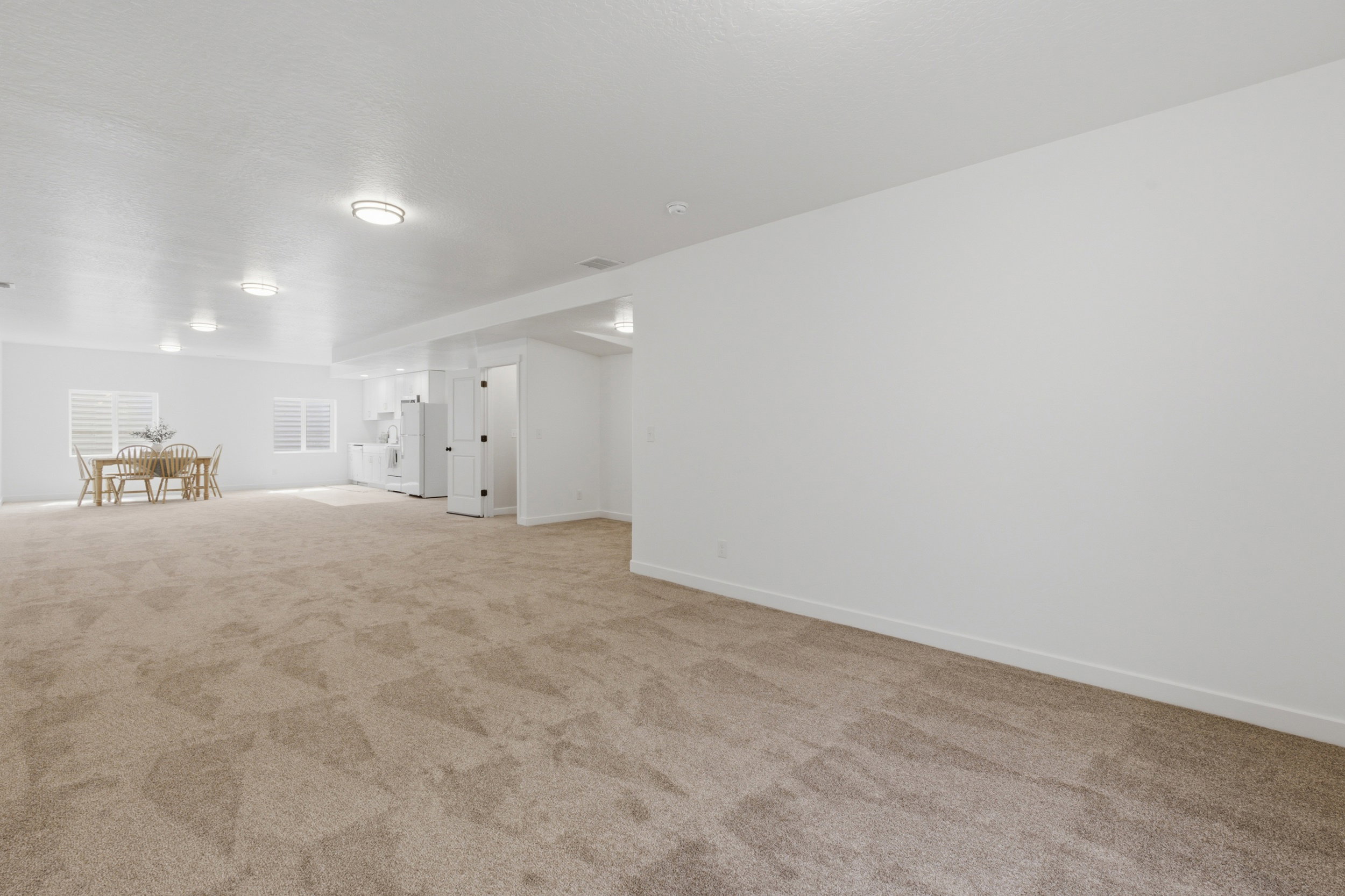 Expansive carpeted area featuring recessed lighting, white walls, and bright baseboards