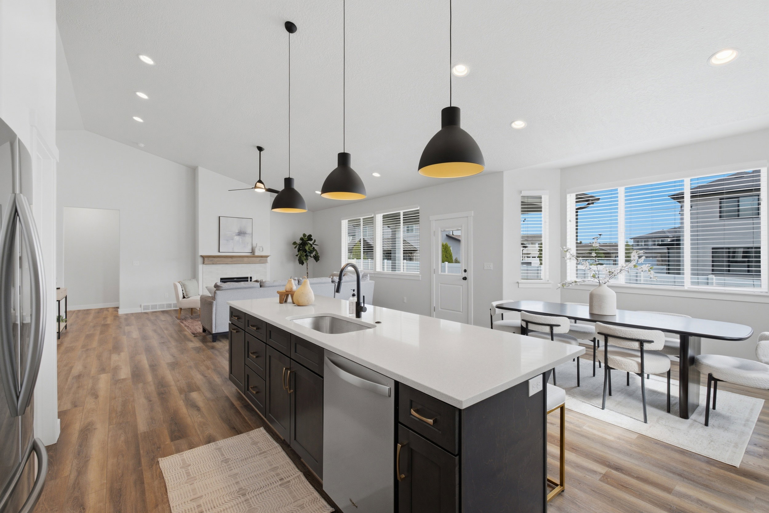 Open-concept living area featuring wood-finish flooring, a kitchen island with a sink and white countertop, and recessed lighting