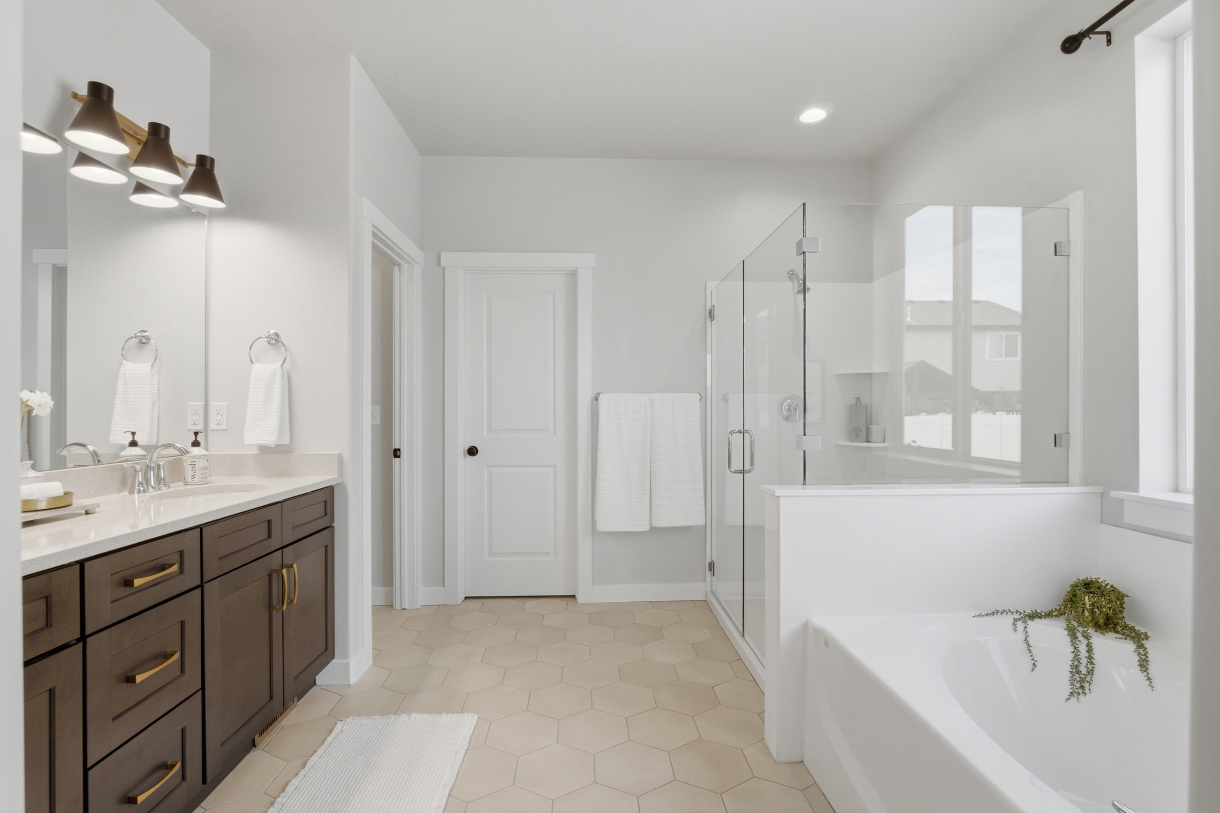 Bathroom featuring a dual vanity with dark wood cabinetry, a glass-enclosed shower, a built-in bathtub, recessed lighting, and hexagonal floor tiling