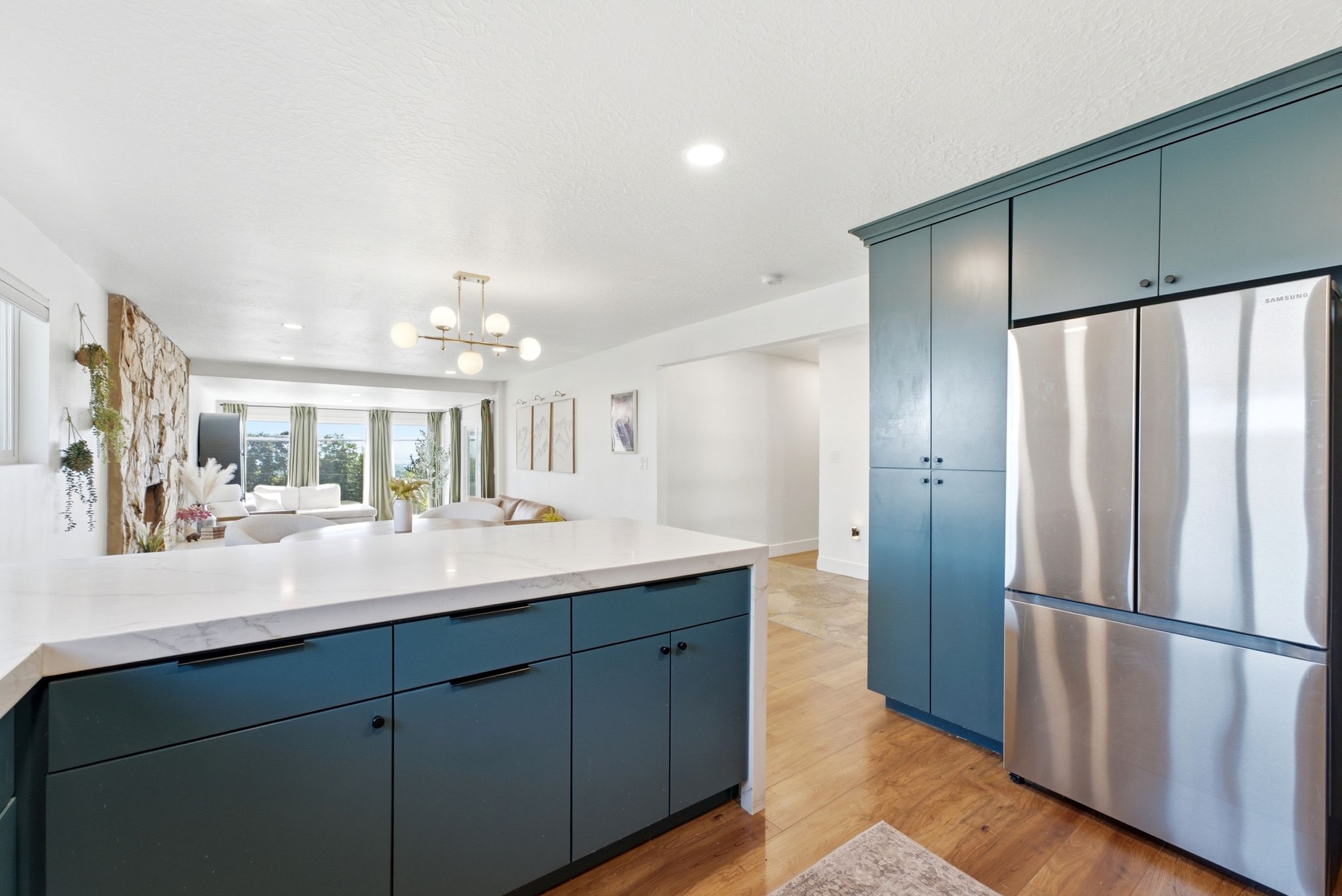 Kitchen island with solid surface countertop, teal cabinetry, and contemporary hardware