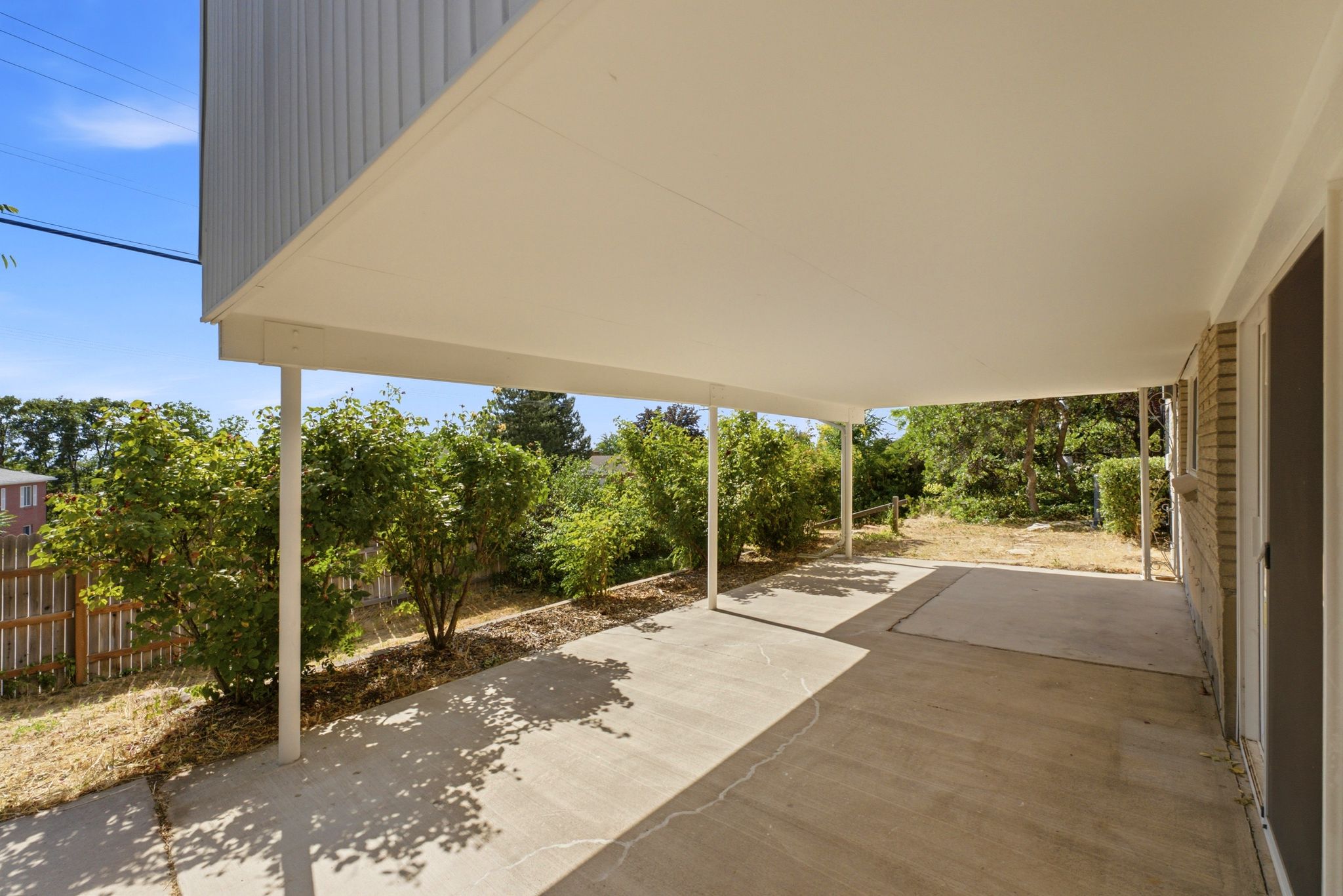 Covered outdoor patio with a concrete surface, supported by white posts