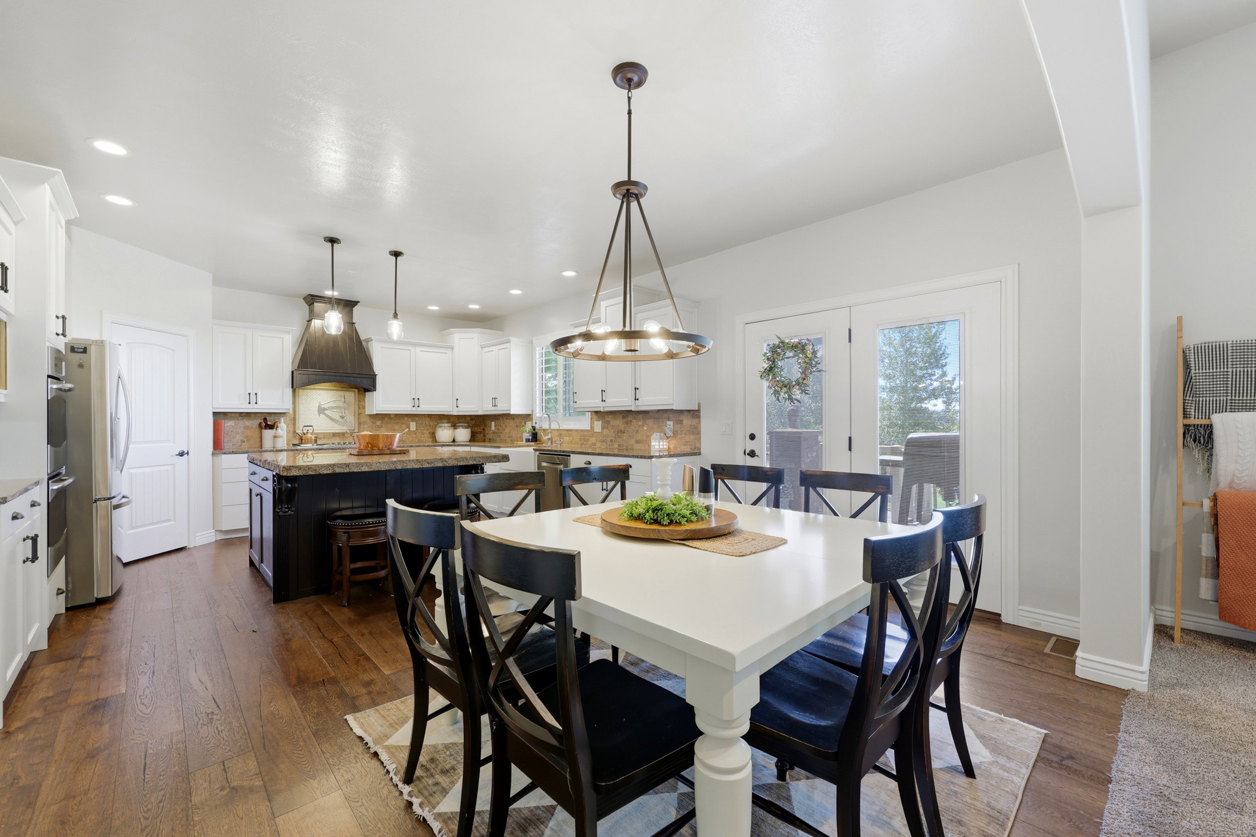 Bright dining area with wood-finish flooring, a contemporary chandelier, and French doors leading outdoors
