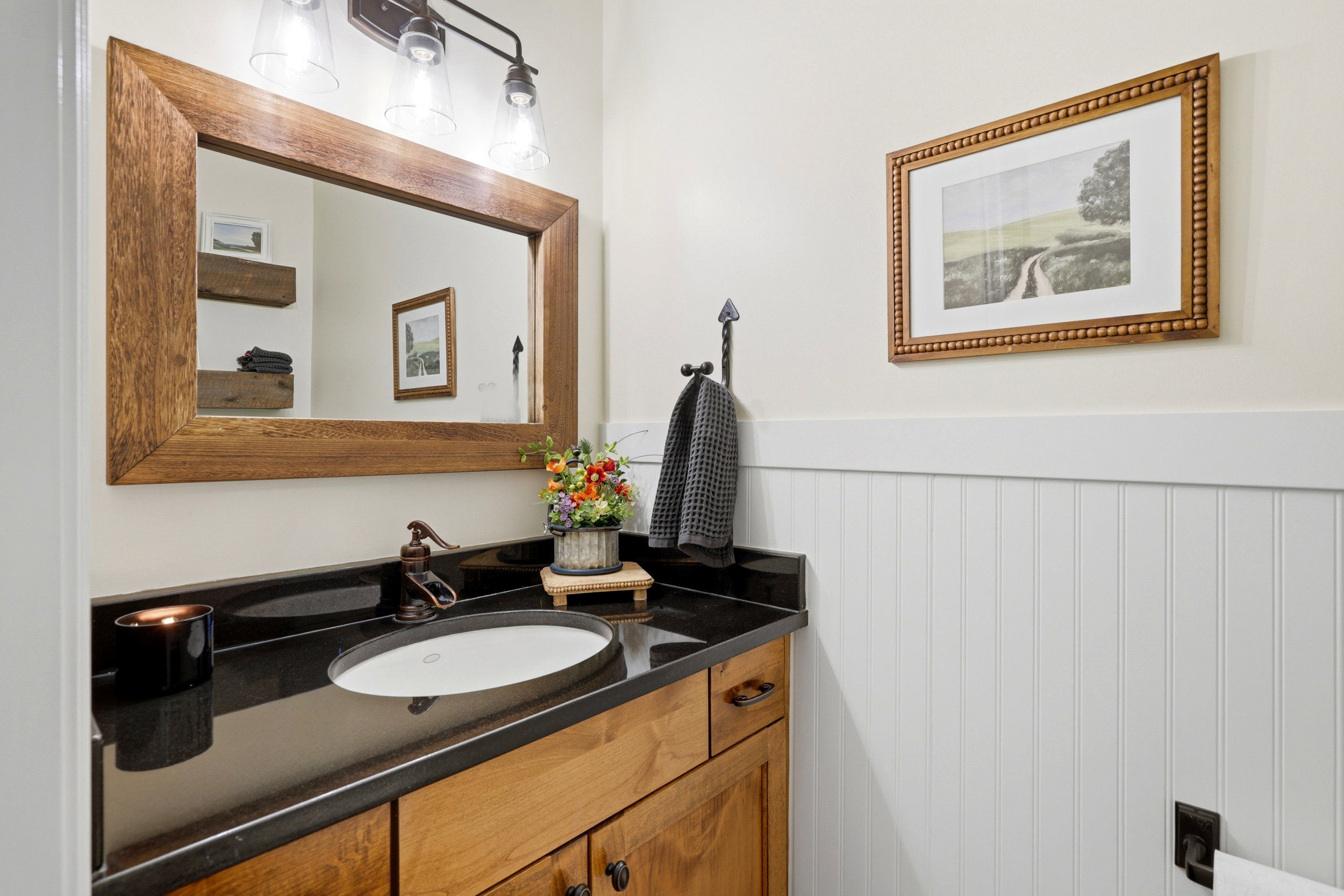 Bathroom vanity featuring a vessel sink, dark countertop, and wood-finish cabinetry