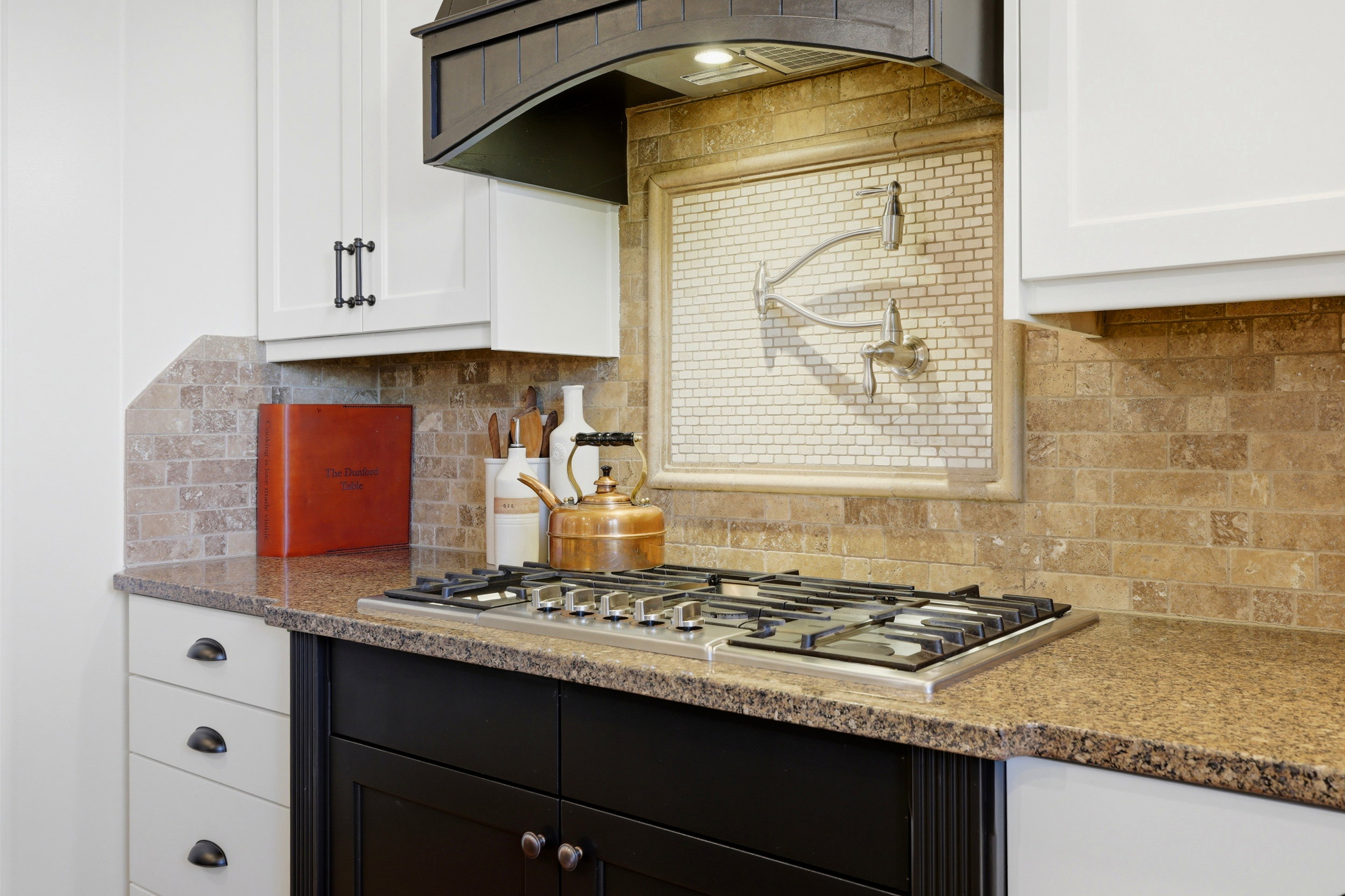 Kitchen featuring a gas range, rich brown countertops, and a full-height tile backsplash with a pot filler