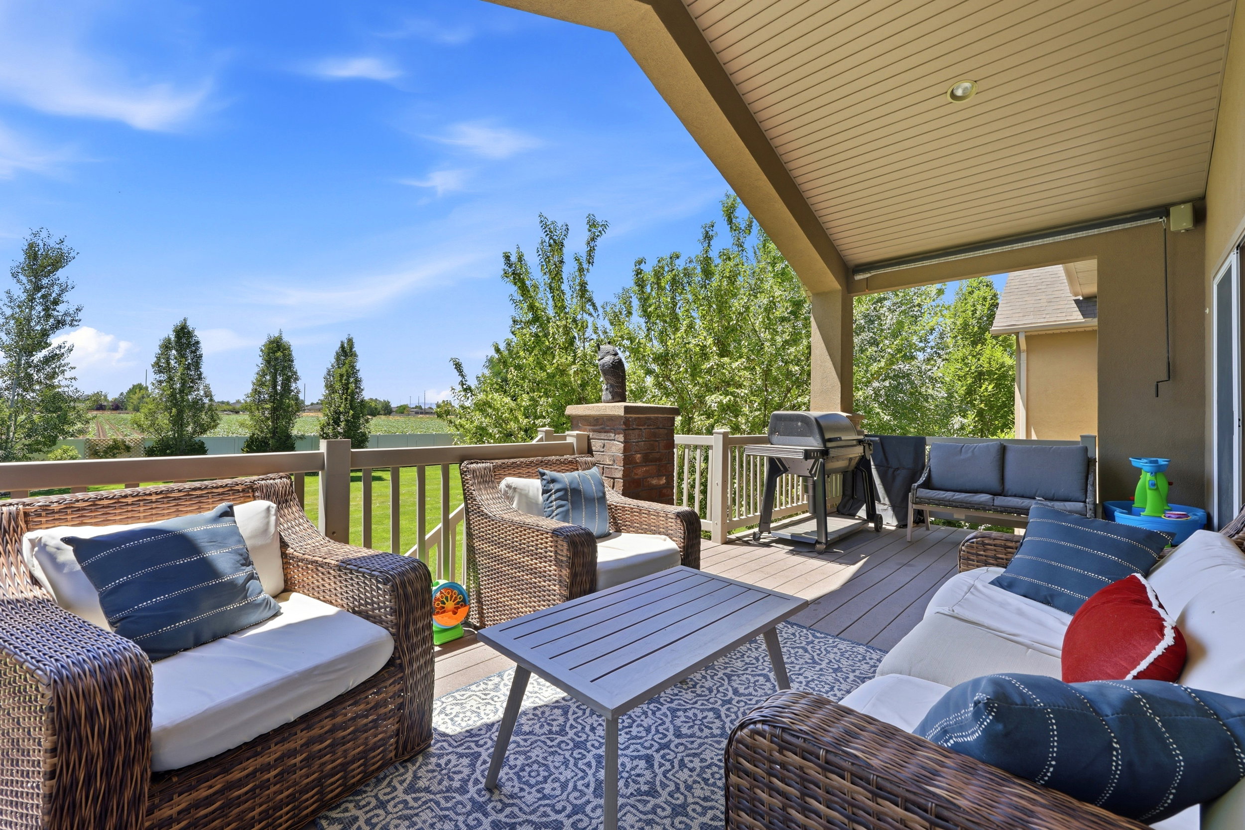 Covered outdoor deck featuring composite decking, a protective railing, and a stone pillar accent