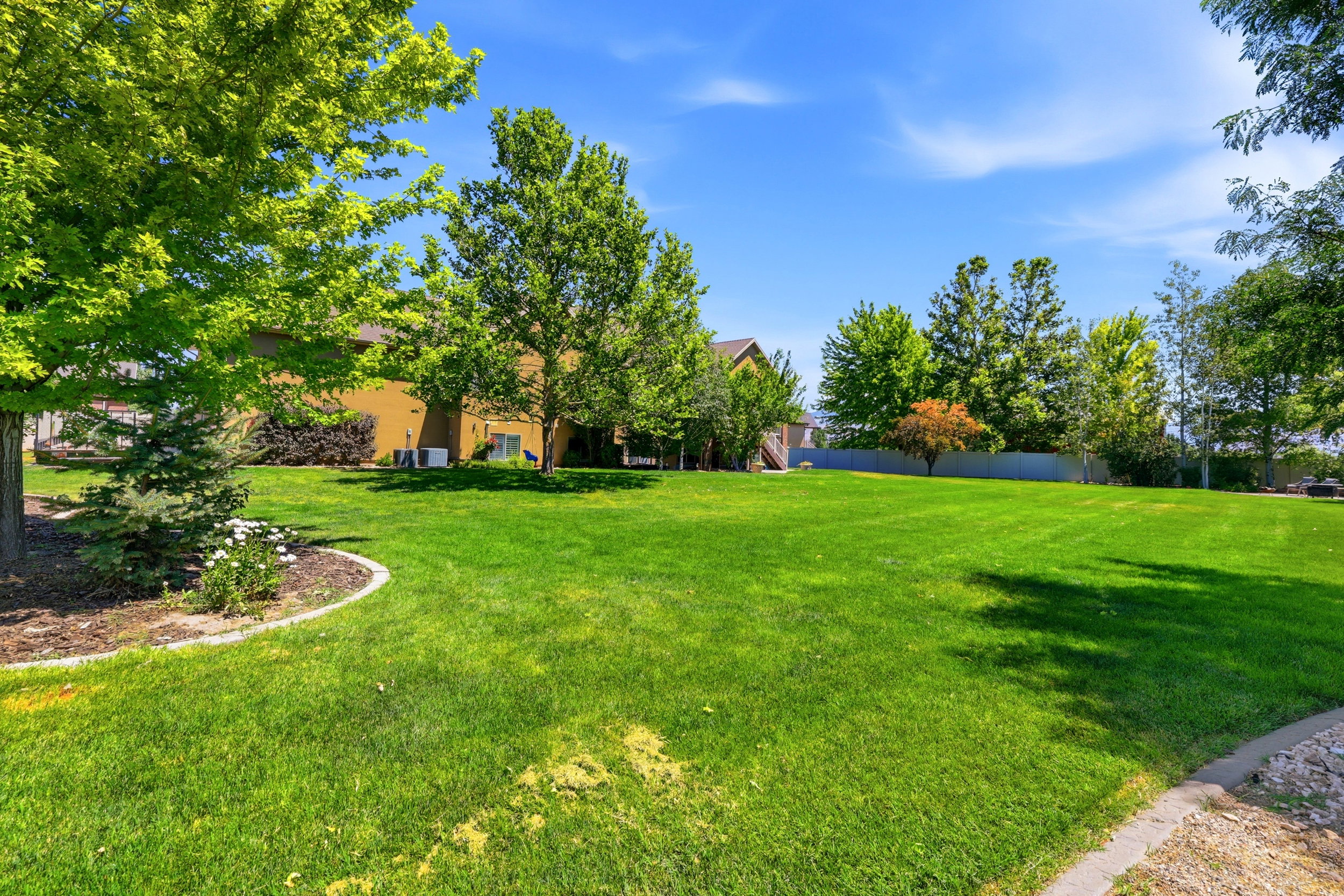 Expansive green lawn with mature trees and a curved landscape border