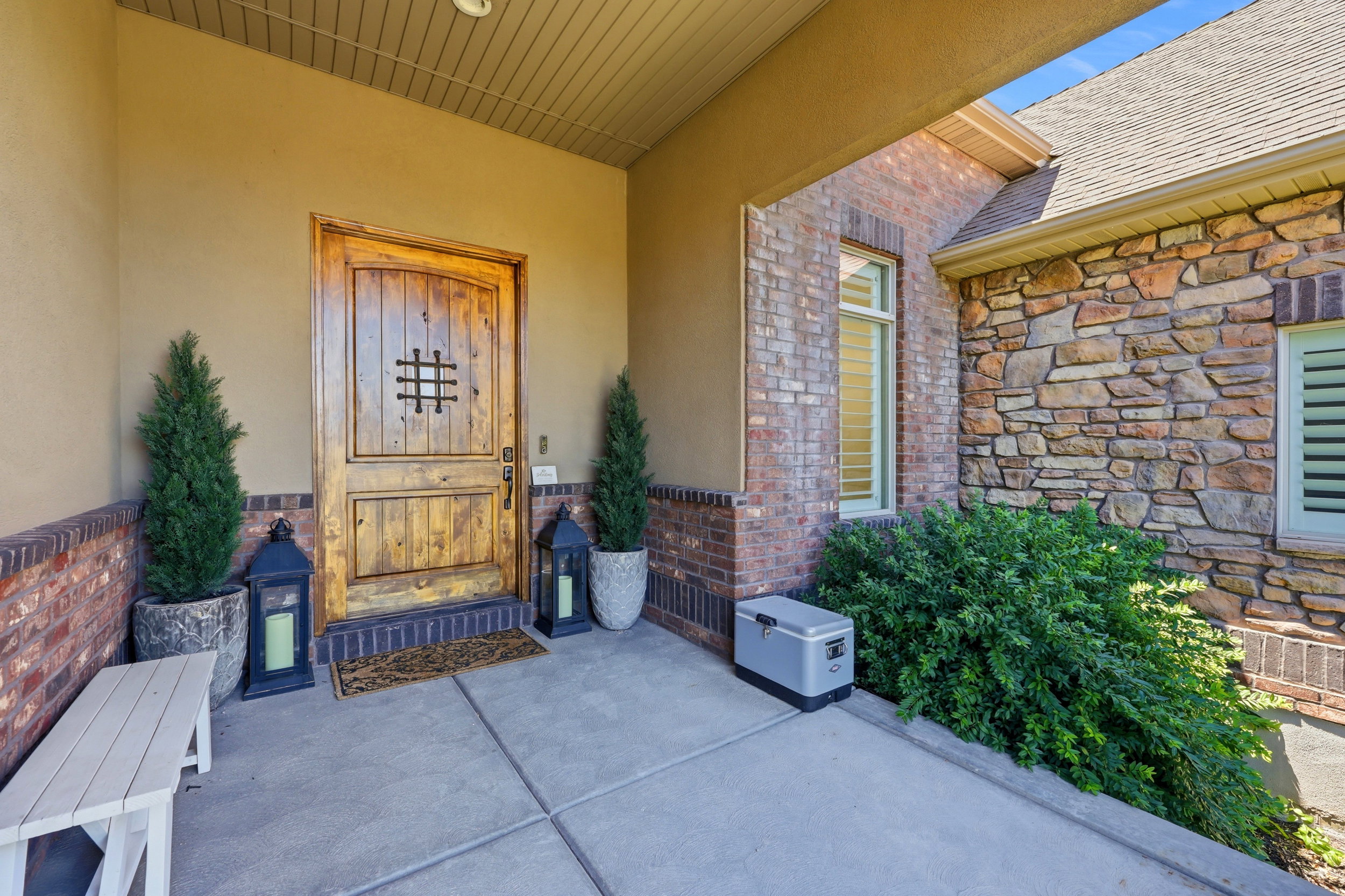 Custom wood entry door with wrought iron detailing, surrounded by multi-tone brick and natural stone siding