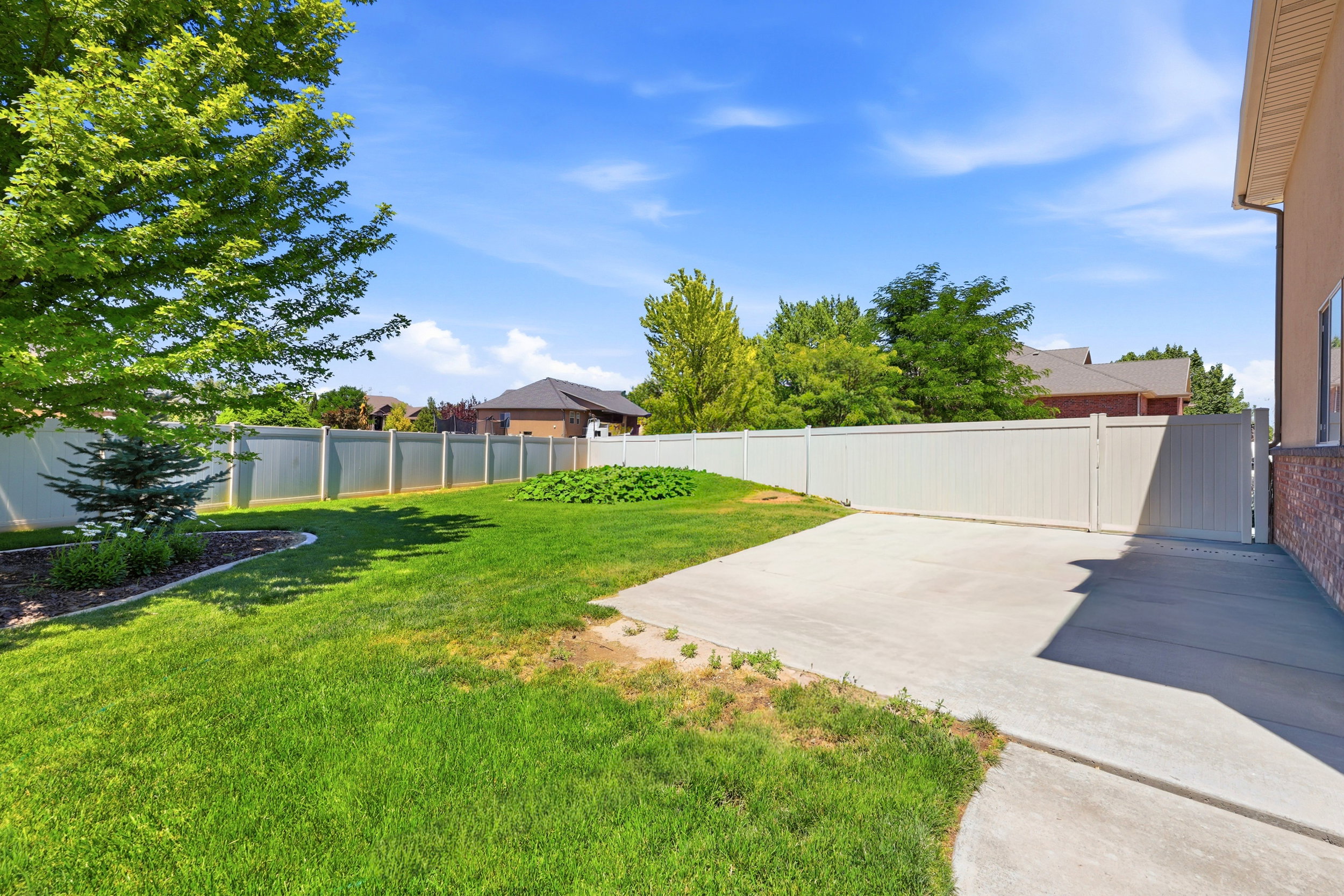 Expansive backyard featuring a manicured lawn, a large concrete patio, and a privacy fence