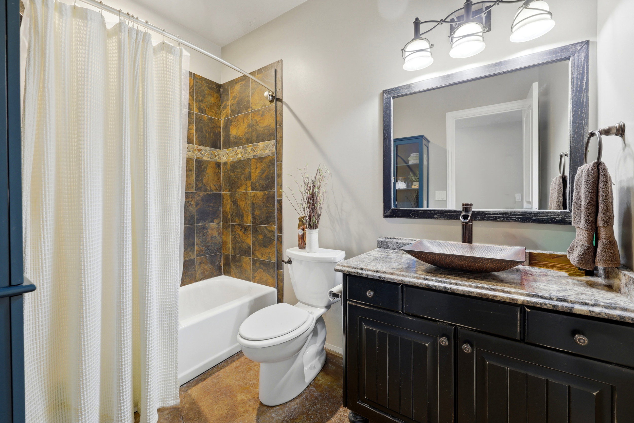 Bathroom featuring a dark wood vanity with a stone countertop, vessel sink, and an oil-rubbed bronze faucet