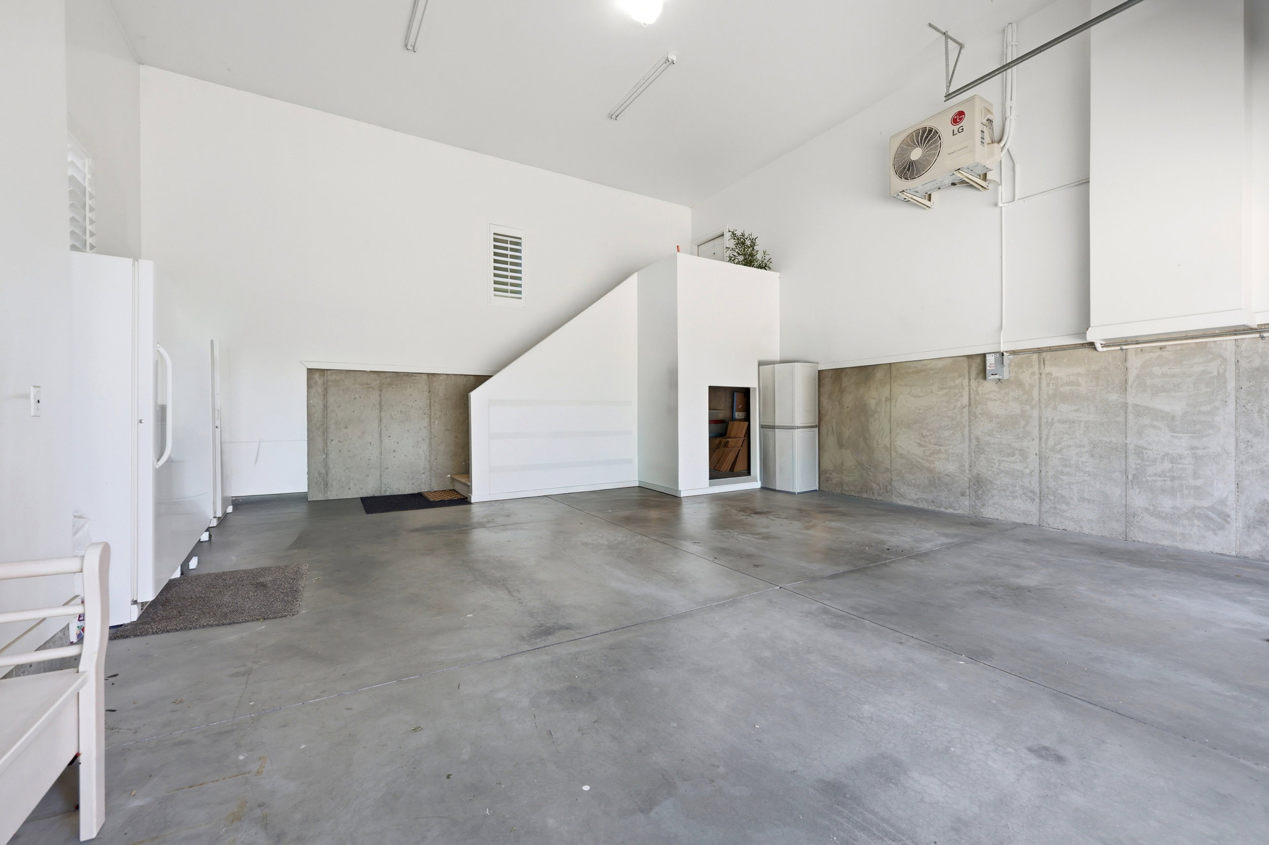 Spacious garage featuring a concrete floor, high ceilings, a built-in storage area, and a wall-mounted mini-split system