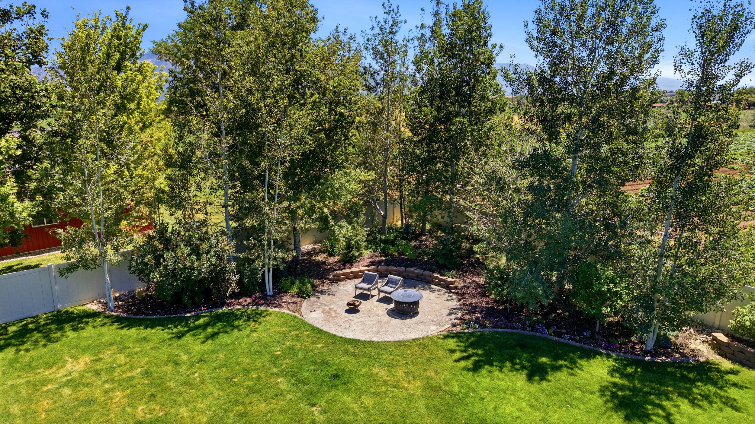 Expansive green lawn with a circular paver patio featuring a built-in fire pit