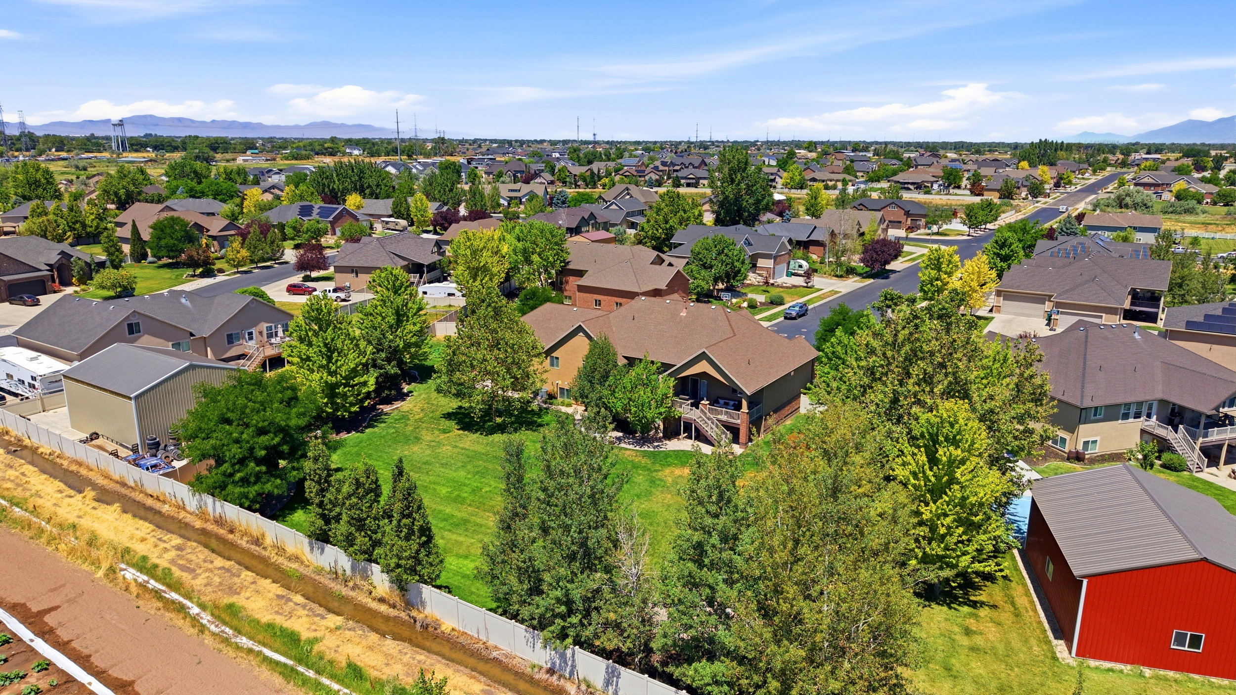 Expansive property with a large, green lawn, mature trees, and a visible red barn structure