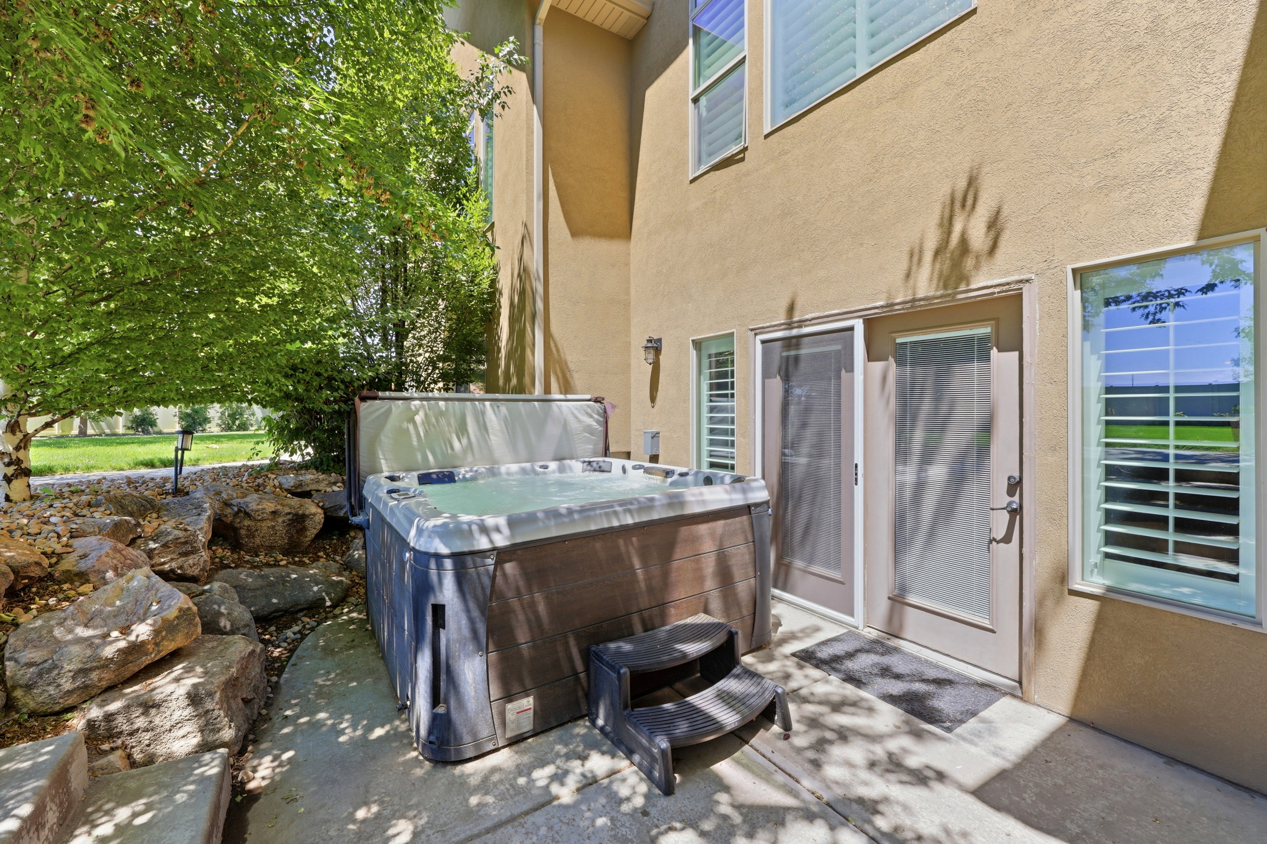 Outdoor patio featuring a built-in spa, concrete surfacing, and natural rock landscaping