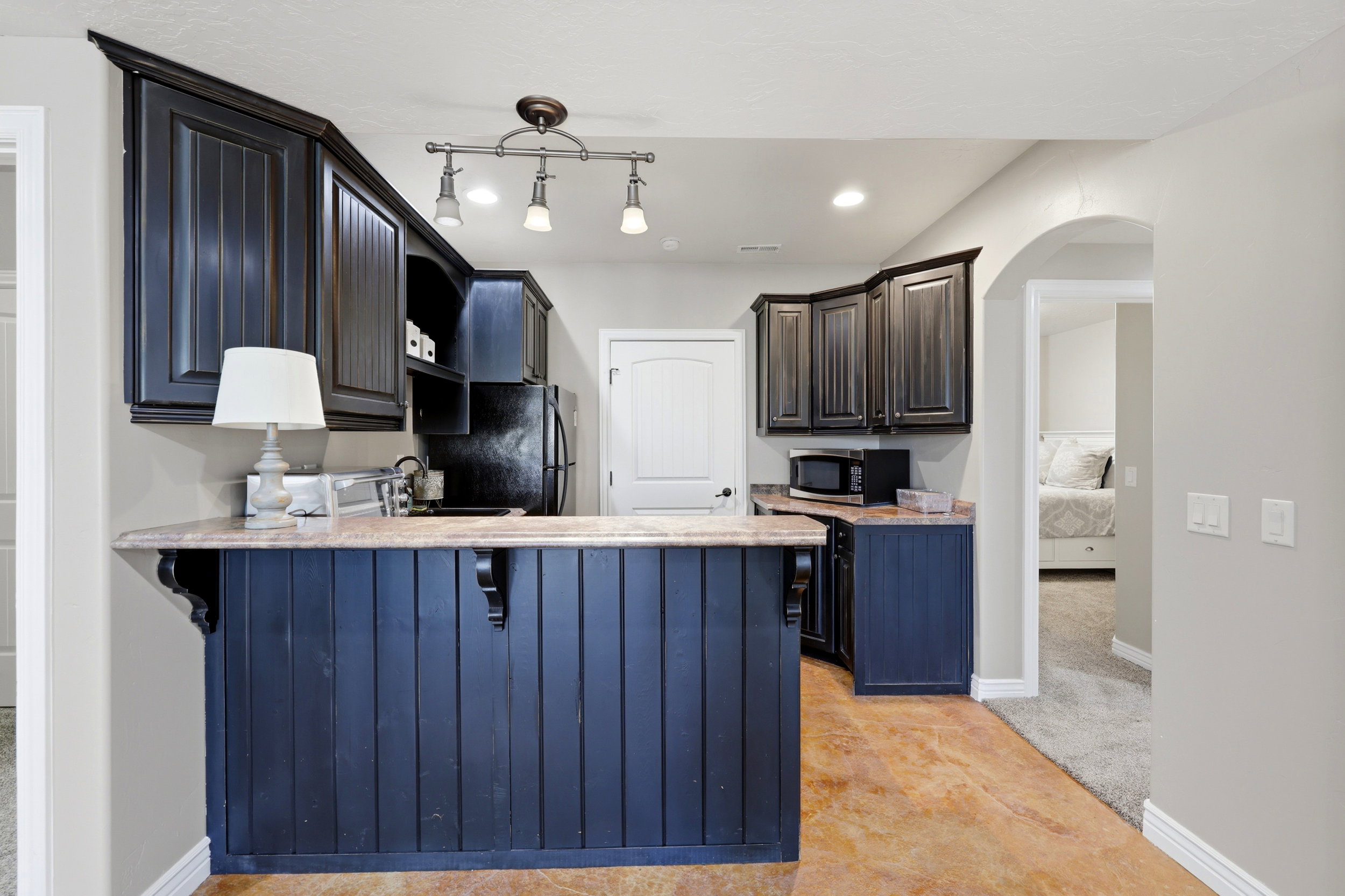 Kitchenette featuring dark-stained cabinetry, light-colored countertops, and recessed lighting