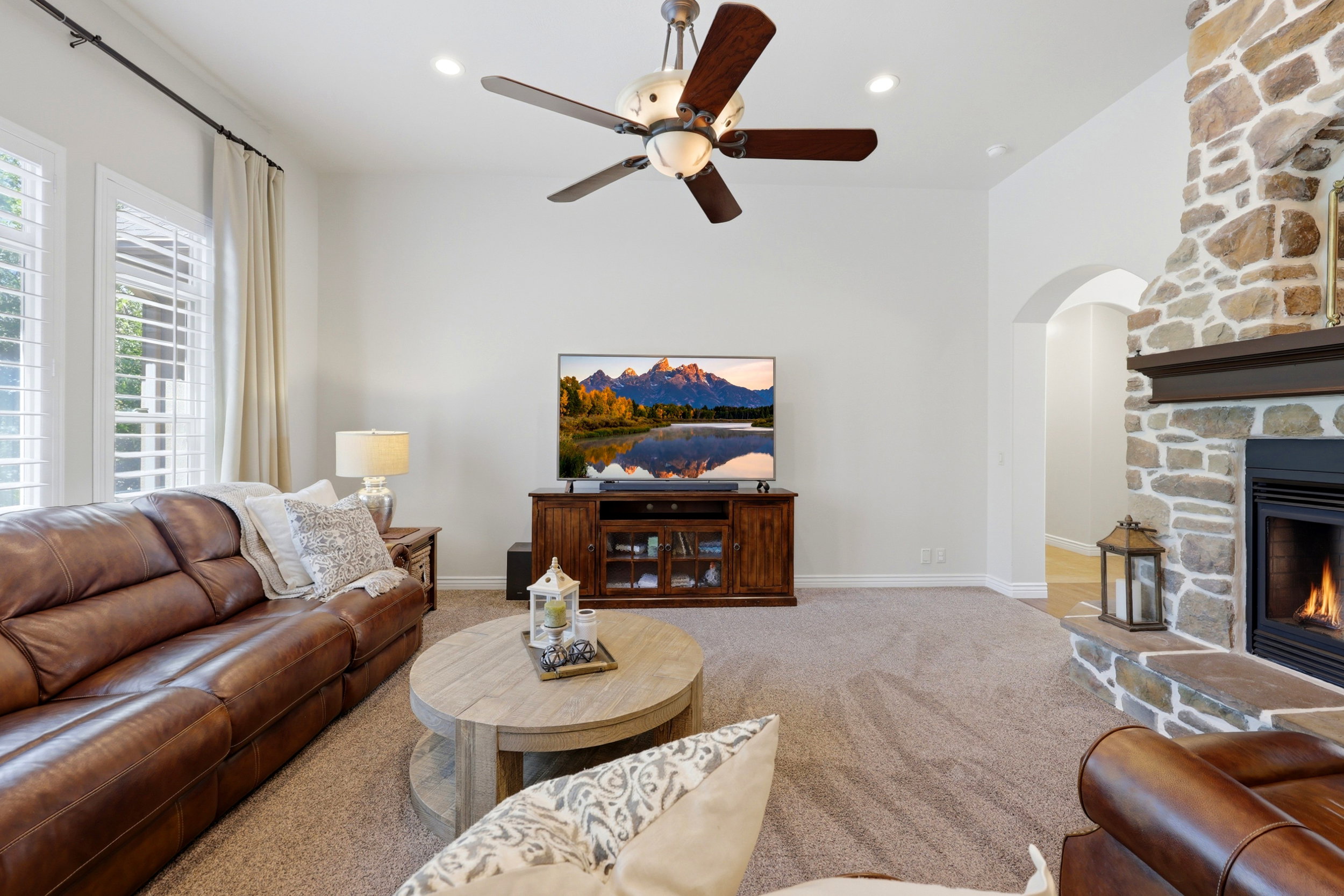 Living area featuring a stone fireplace with a wood mantle, recessed lighting, and a ceiling fan
