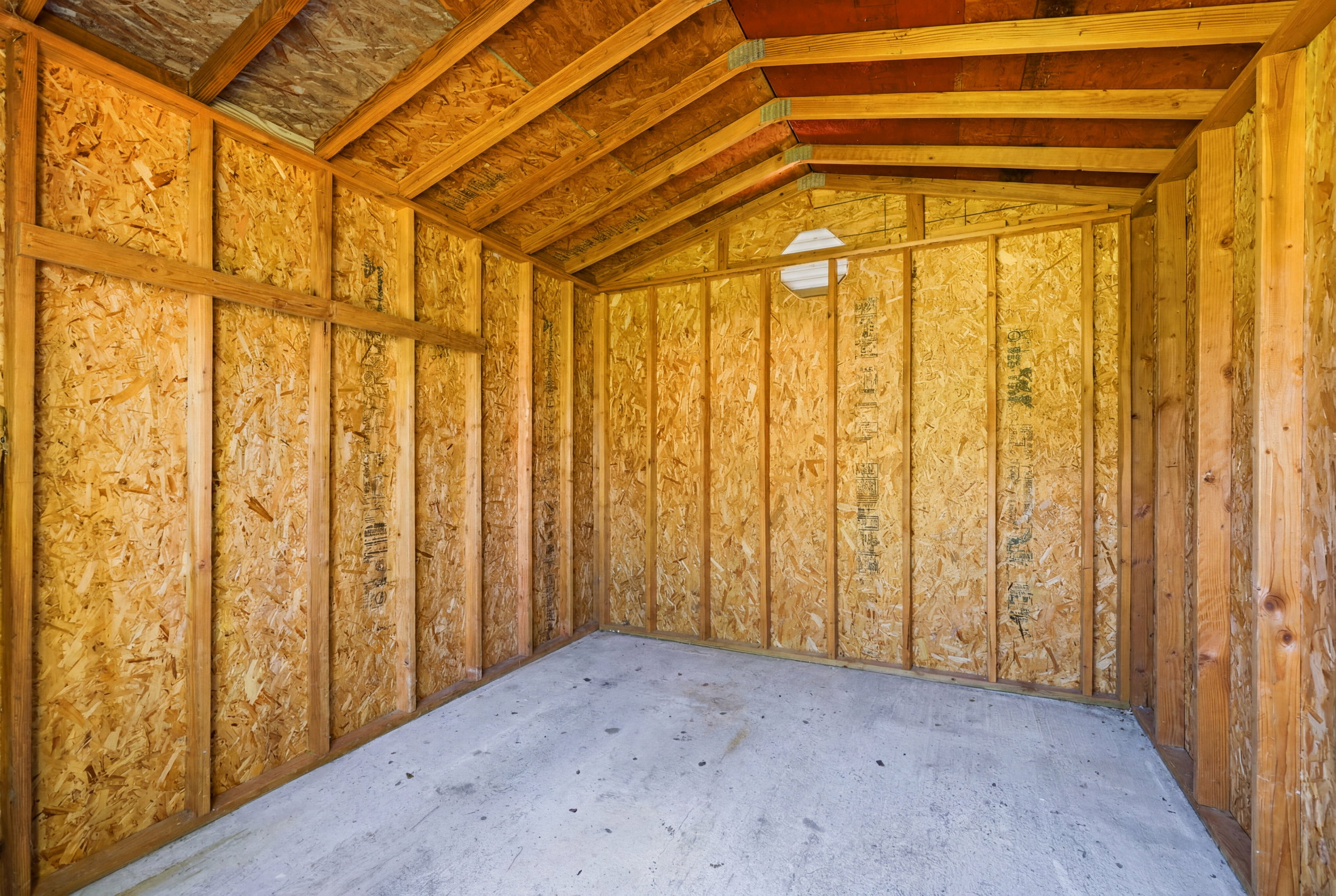 Unfinished interior structure featuring exposed wood framing, oriented strand board (OSB) walls, and an open truss ceiling