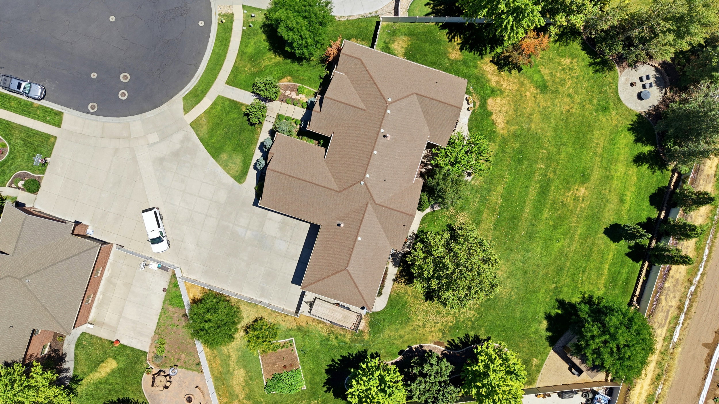 Expansive property featuring a cul-de-sac location with a large concrete driveway, mature landscaping, and a substantial grassy yard