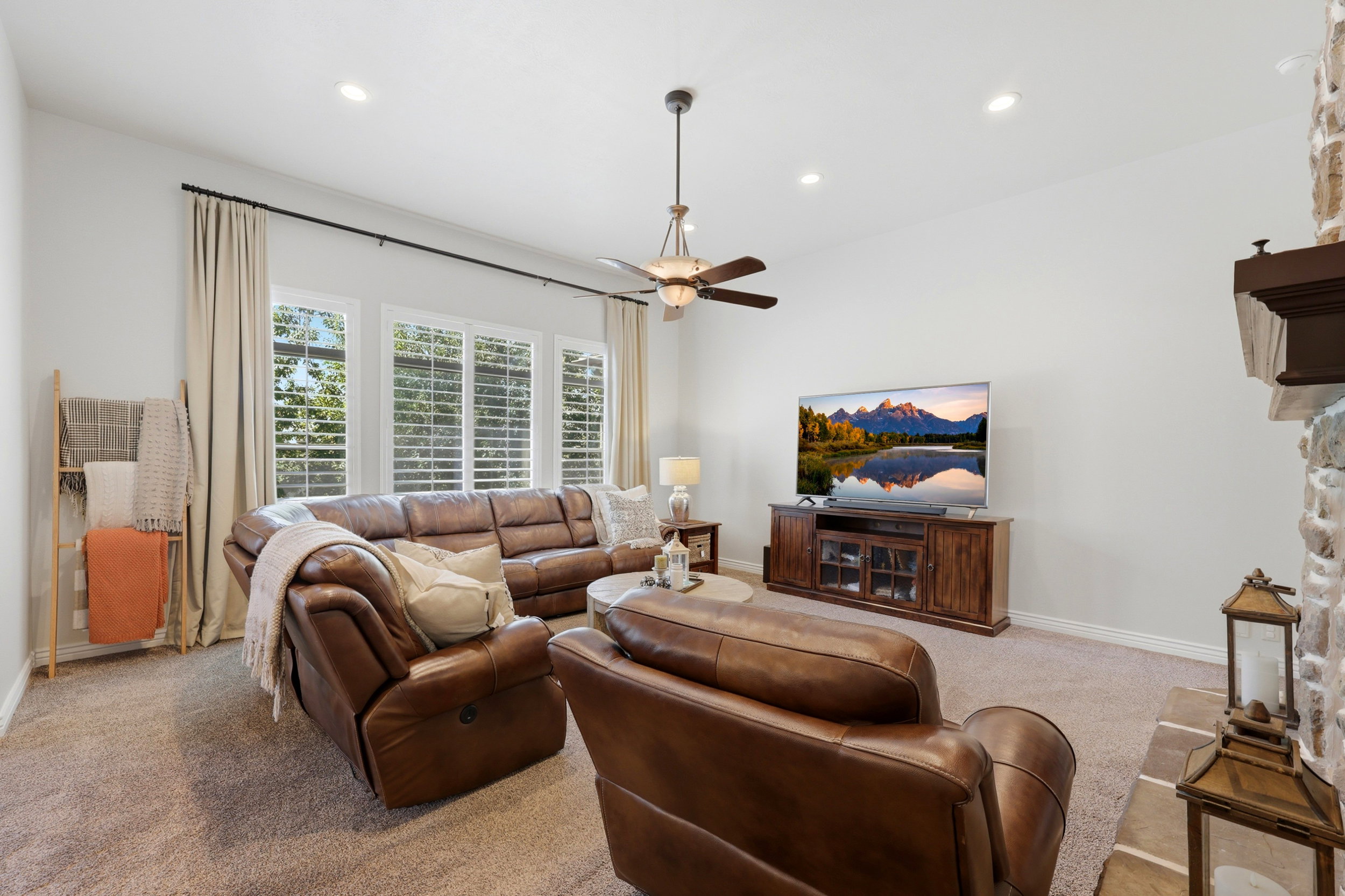 Living area featuring a stone fireplace with a wood mantle, recessed lighting, a ceiling fan, and carpet flooring