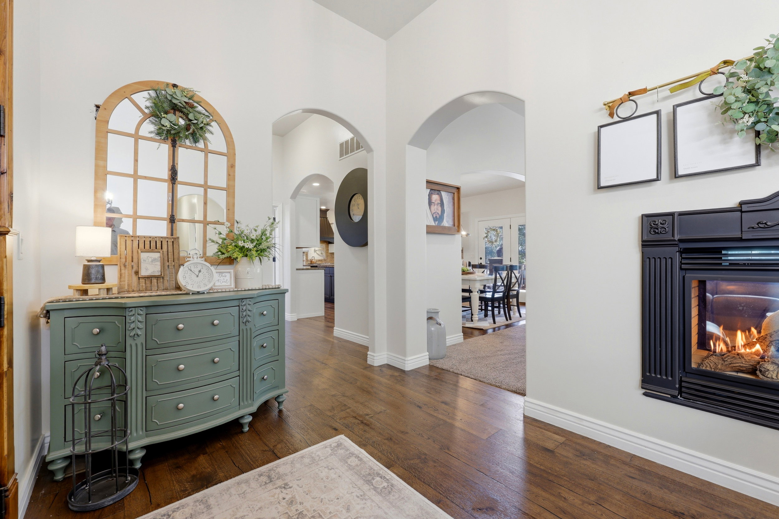 Foyer featuring wood-finish flooring, high ceilings, arched doorways, and a built-in fireplace