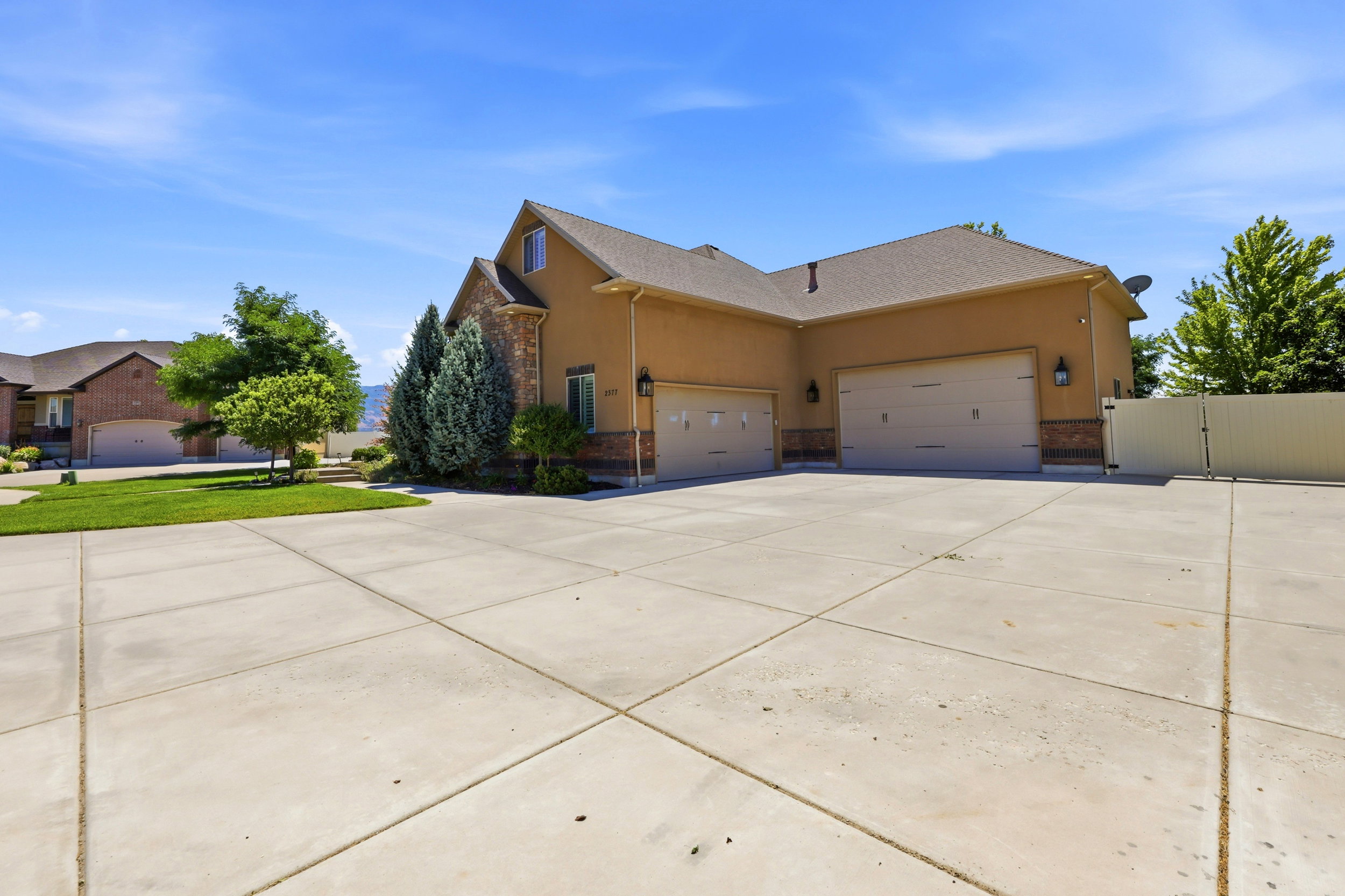 Stucco exterior with stone accents, multiple garage doors, and a concrete drive