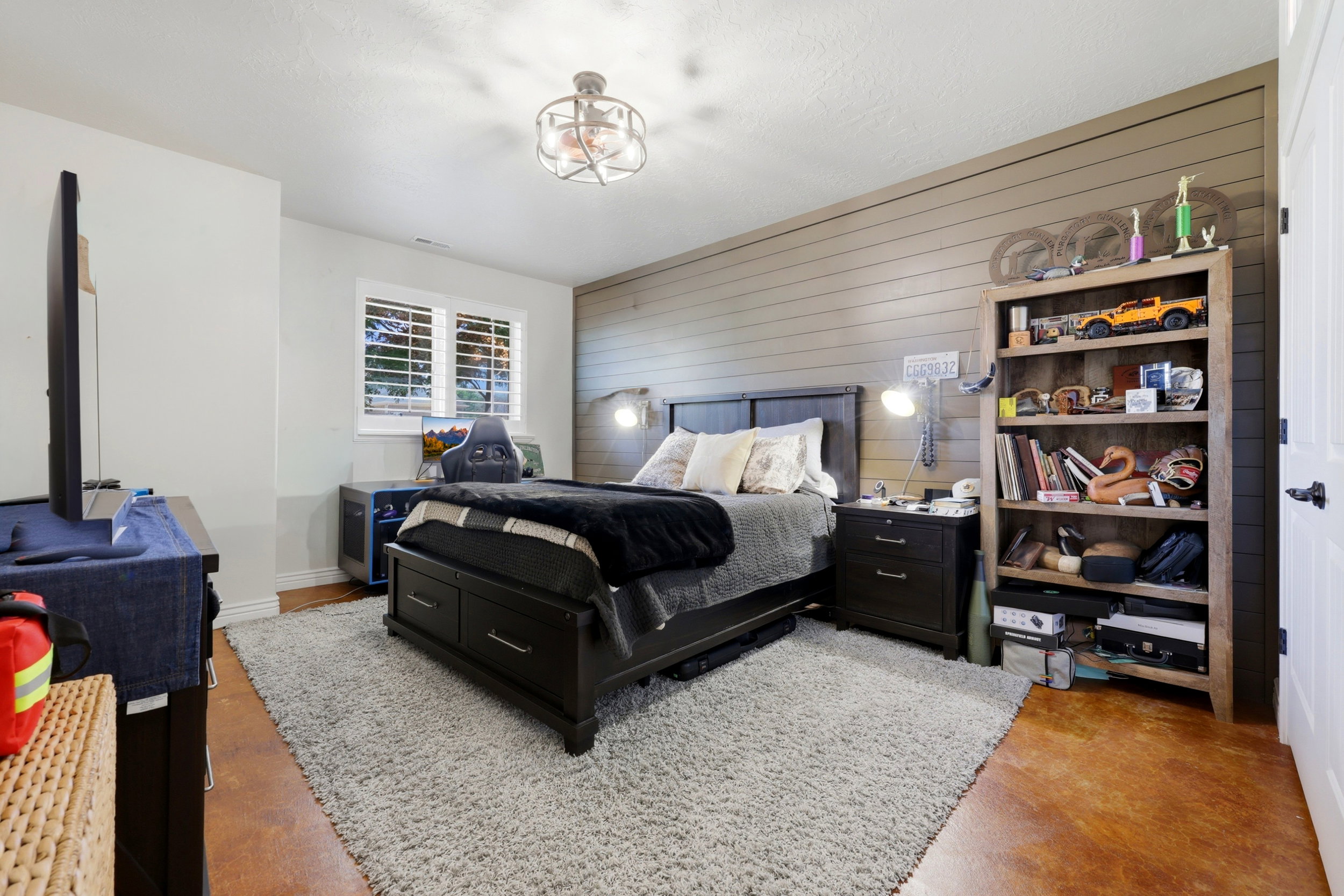 Spacious bedroom featuring a shiplap accent wall, white-painted walls, and a ceiling fan with integrated lighting