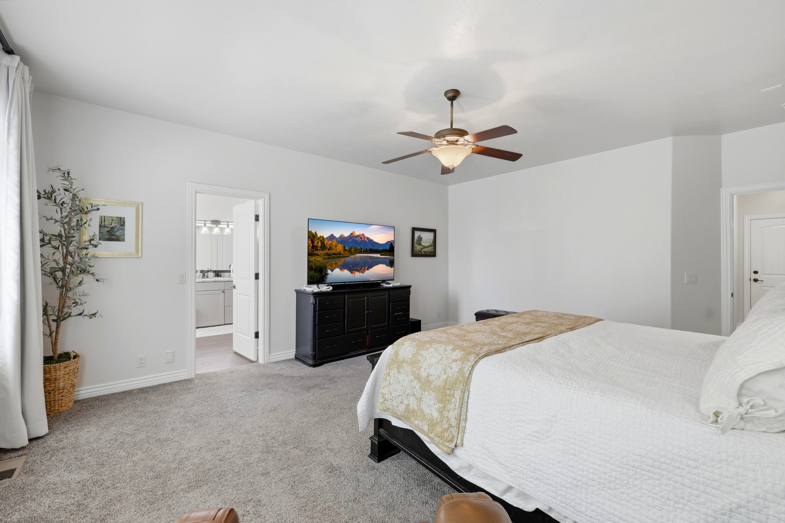 Spacious room featuring neutral carpeting, white wall finishes, and a ceiling fan with integrated lighting