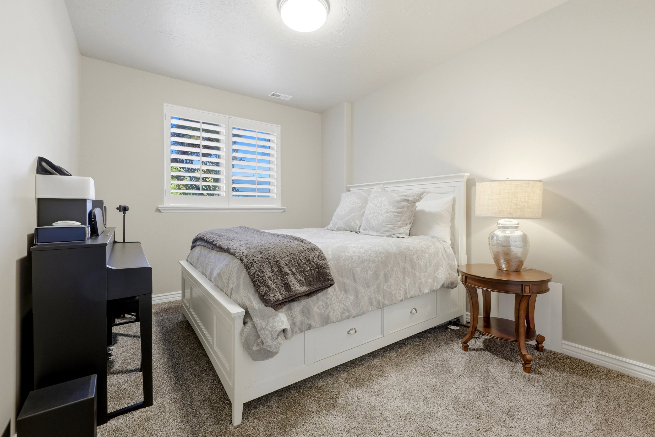 Bedroom featuring neutral wall paint, carpet flooring, a window with plantation shutters, and a built-in bed frame with storage drawers