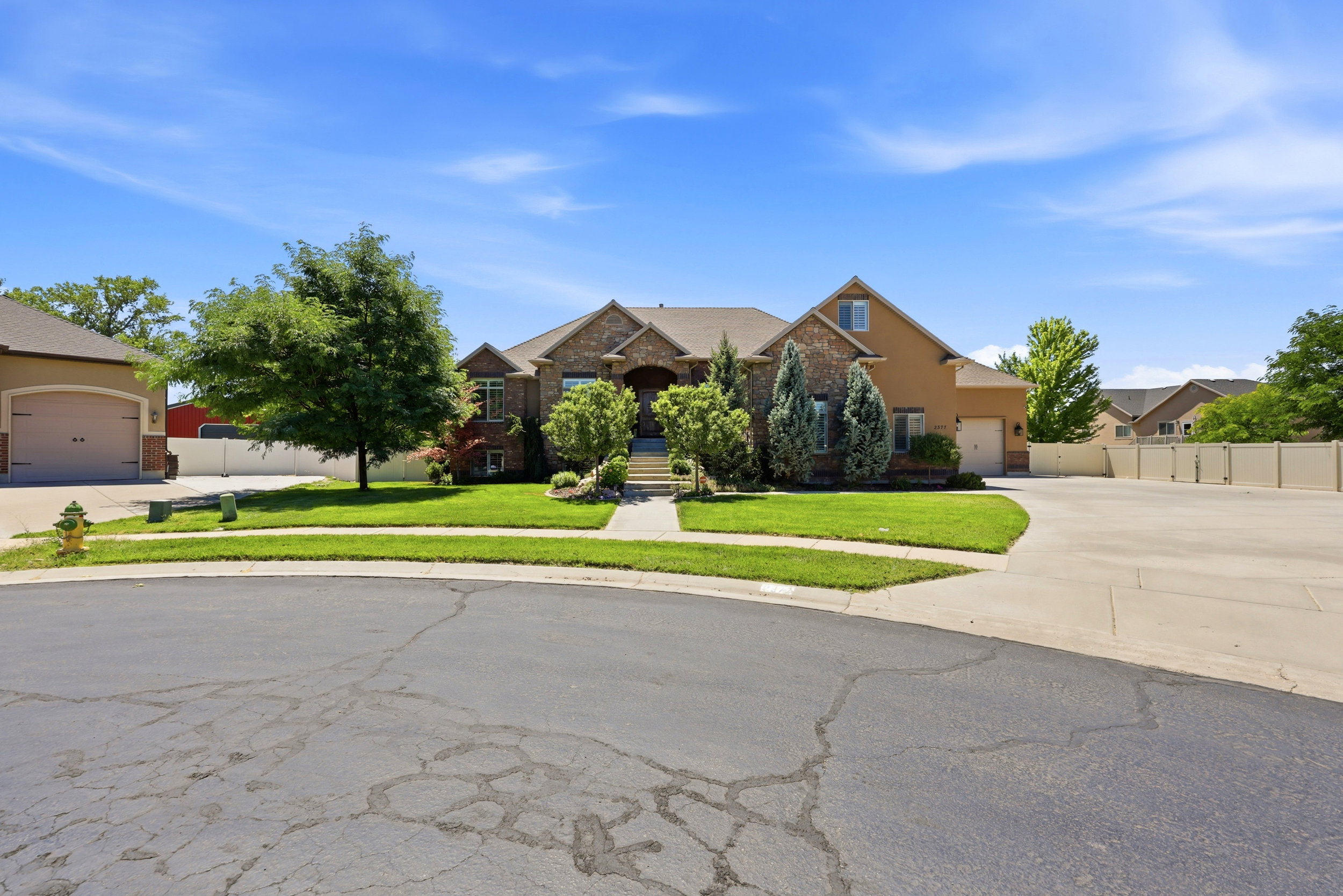 Traditional style residence featuring a stone and stucco exterior, a prominent front entrance with steps, mature landscaping, and a well-maintained lawn