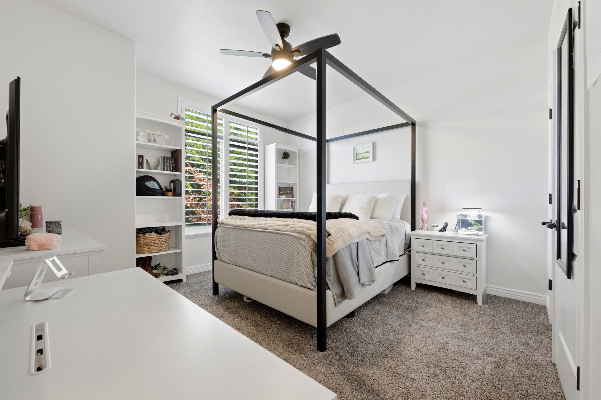 Neutral wall paint, plush carpet flooring, recessed lighting, ceiling fan, and window with plantation shutters
