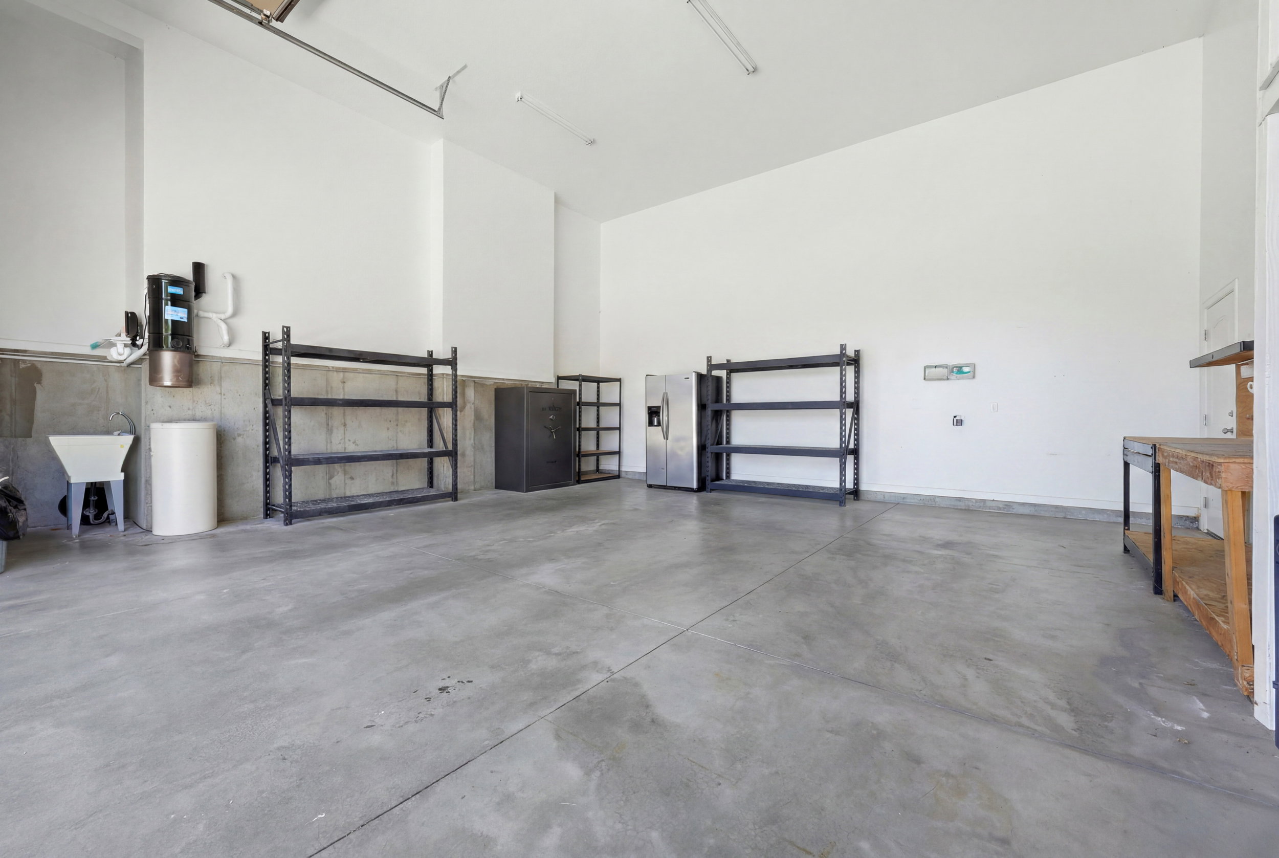 Spacious garage featuring a concrete floor, painted white walls, and a utility sink