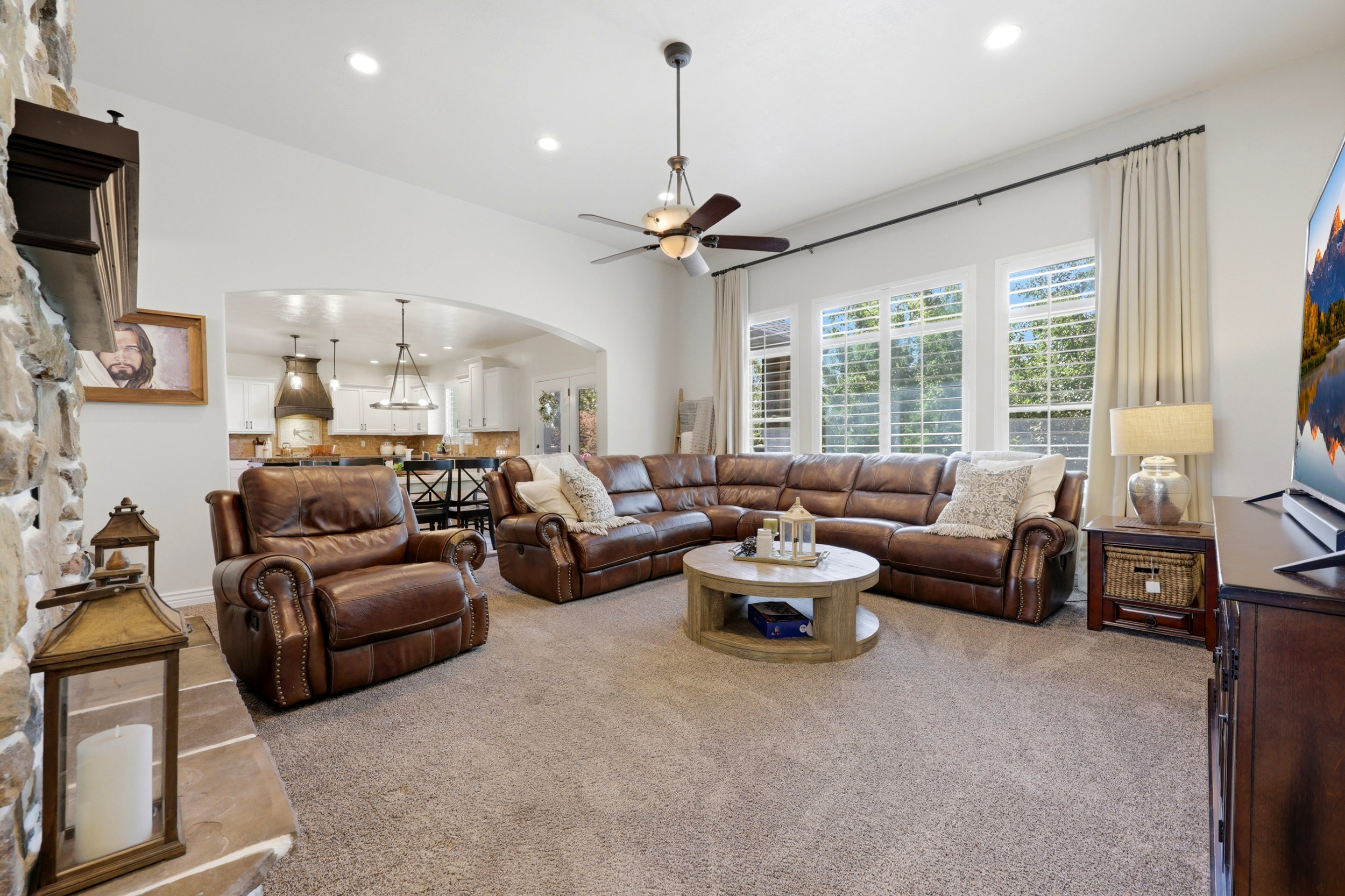Spacious living area featuring high ceilings, recessed lighting, and a stone-clad fireplace